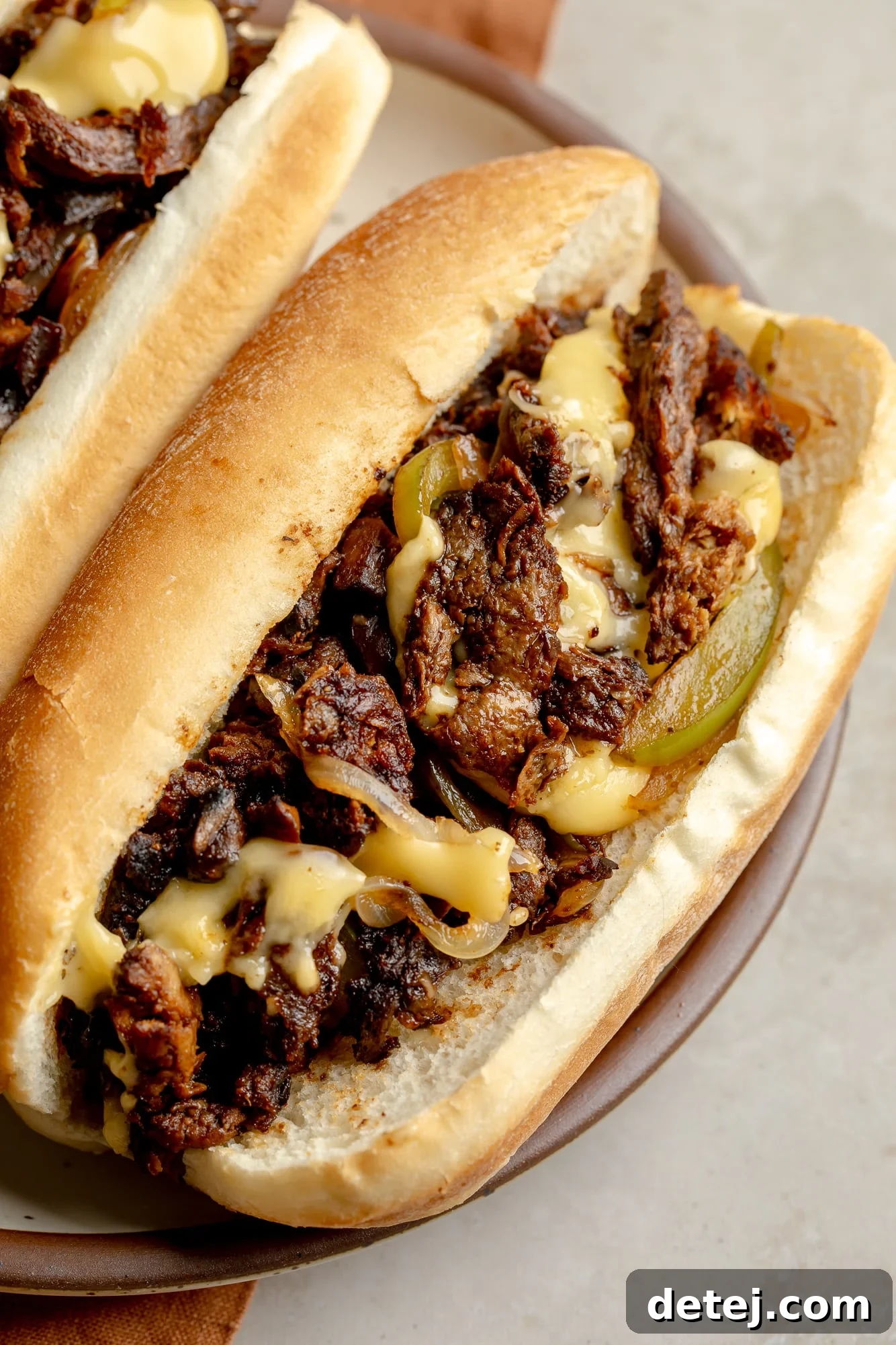 Plant-Based Philly Delight 2 Close up on a vegan philly cheesesteak sandwich, showcasing the filling and melted cheese.