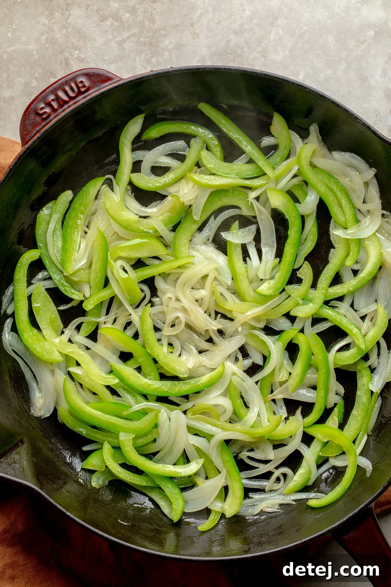 Plant-Based Philly Delight 3 Cooking sliced onions and green bell peppers in a large skillet until softened.