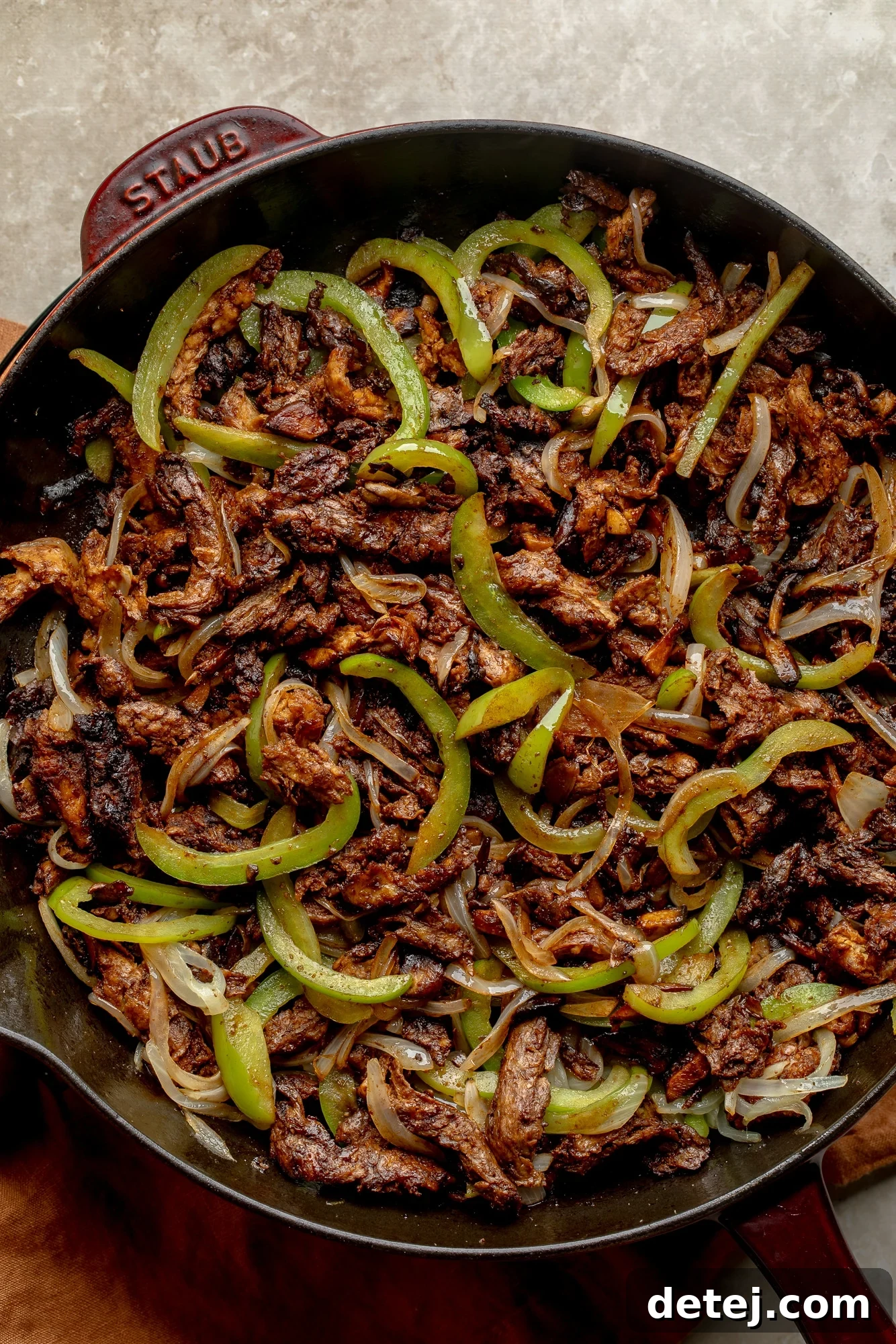 Plant-Based Philly Delight 5 Cooking a soy curl, onion, and bell pepper filling for vegan philly cheesesteak sandwiches in a large skillet.
