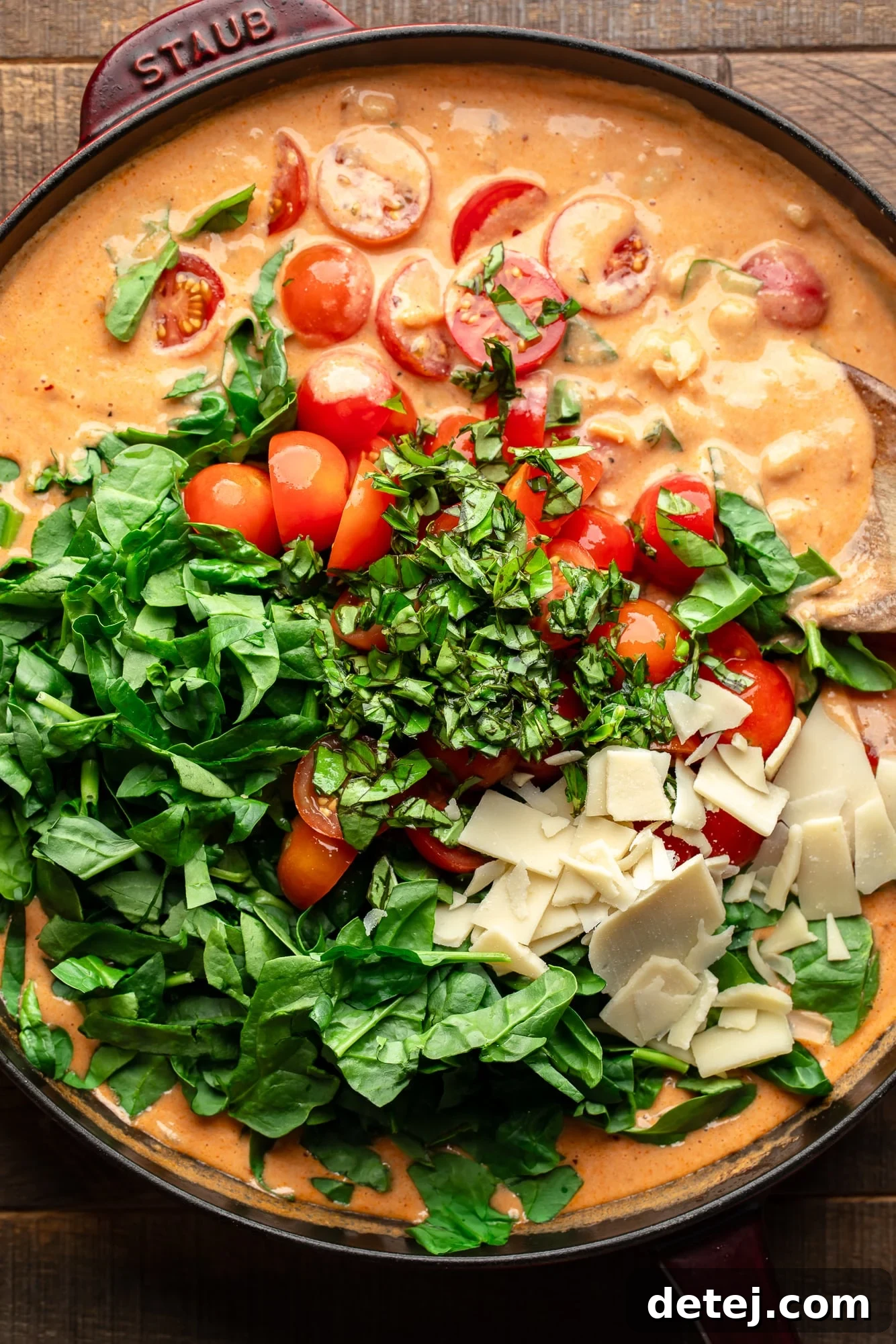 The vibrant ingredients for creamy skillet white beans beautifully arranged in a large pan before cooking, showcasing the fresh produce and rich tomato paste.