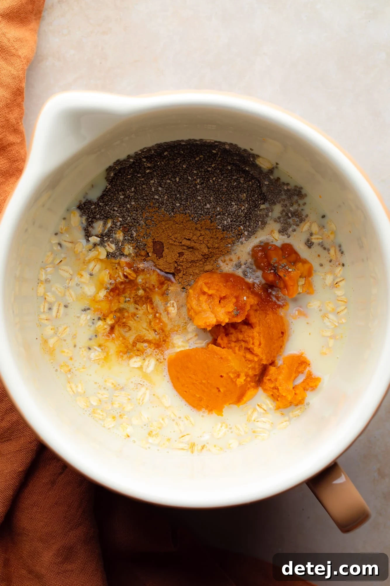 the ingredients for pumpkin overnight oats in a large white bowl.