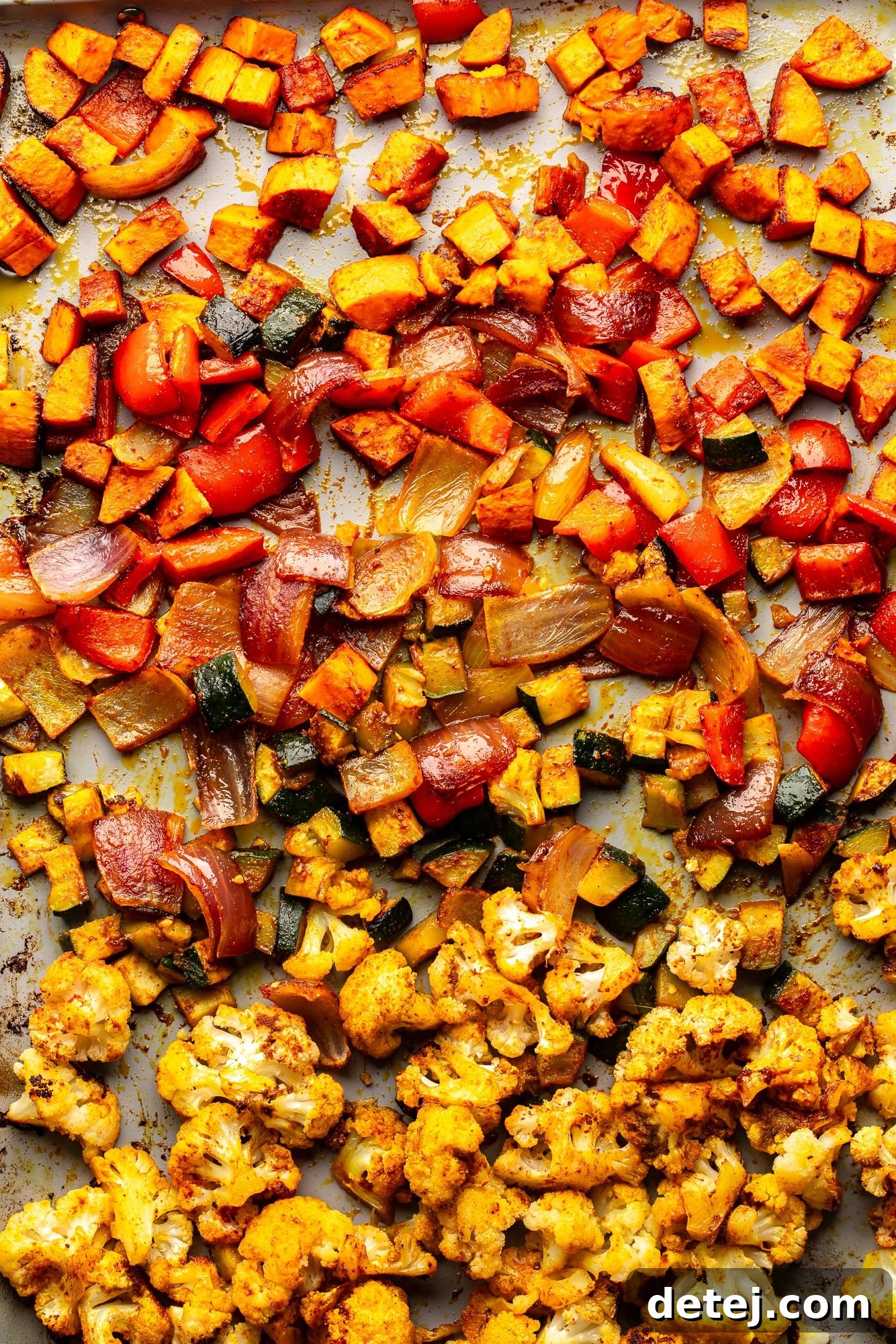 Overhead view of a medley of perfectly roasted vegetables on a sheet pan, golden and tender.