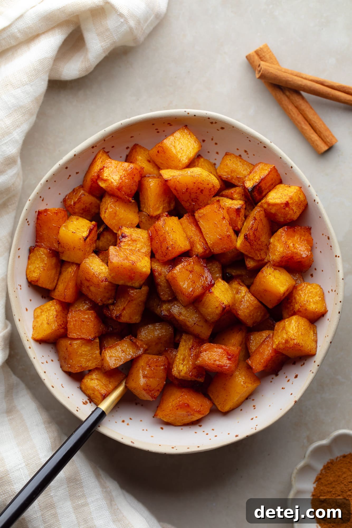 overhead view of air fryer butternut squash cubes in a white bowl.