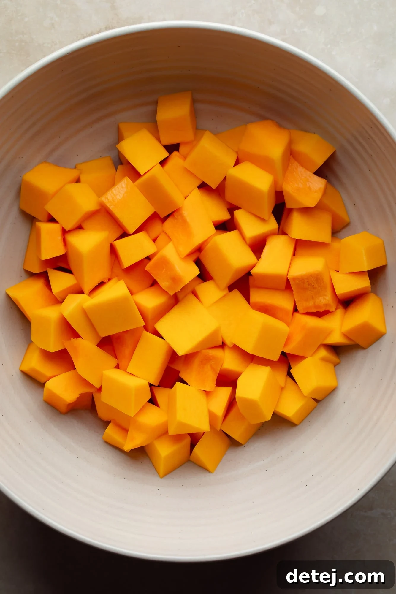overhead view of raw butternut squash cubes in a large bowl.