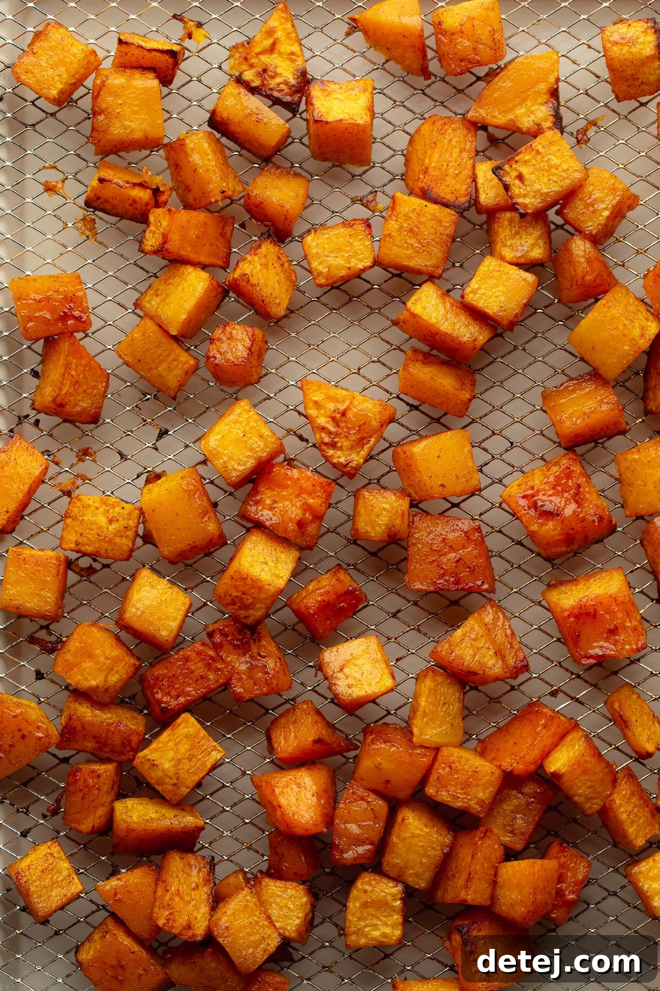 overhead view of air fryer butternut squash cubes in an even layer in an air fryer basket.