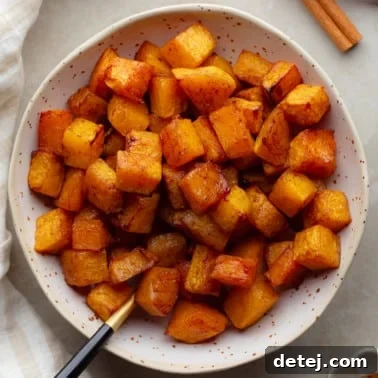 overhead view of air fryer butternut squash cubes in a white bowl.