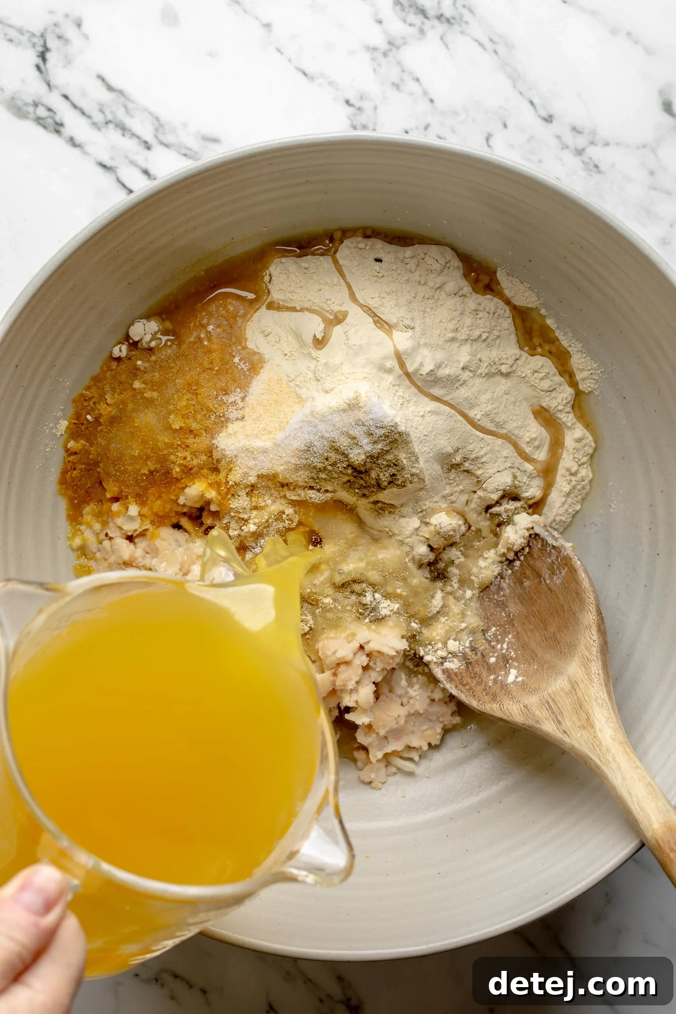 Pouring broth overtop of vegan cutlet ingredients in a large bowl, highlighting the wet and dry mixture.