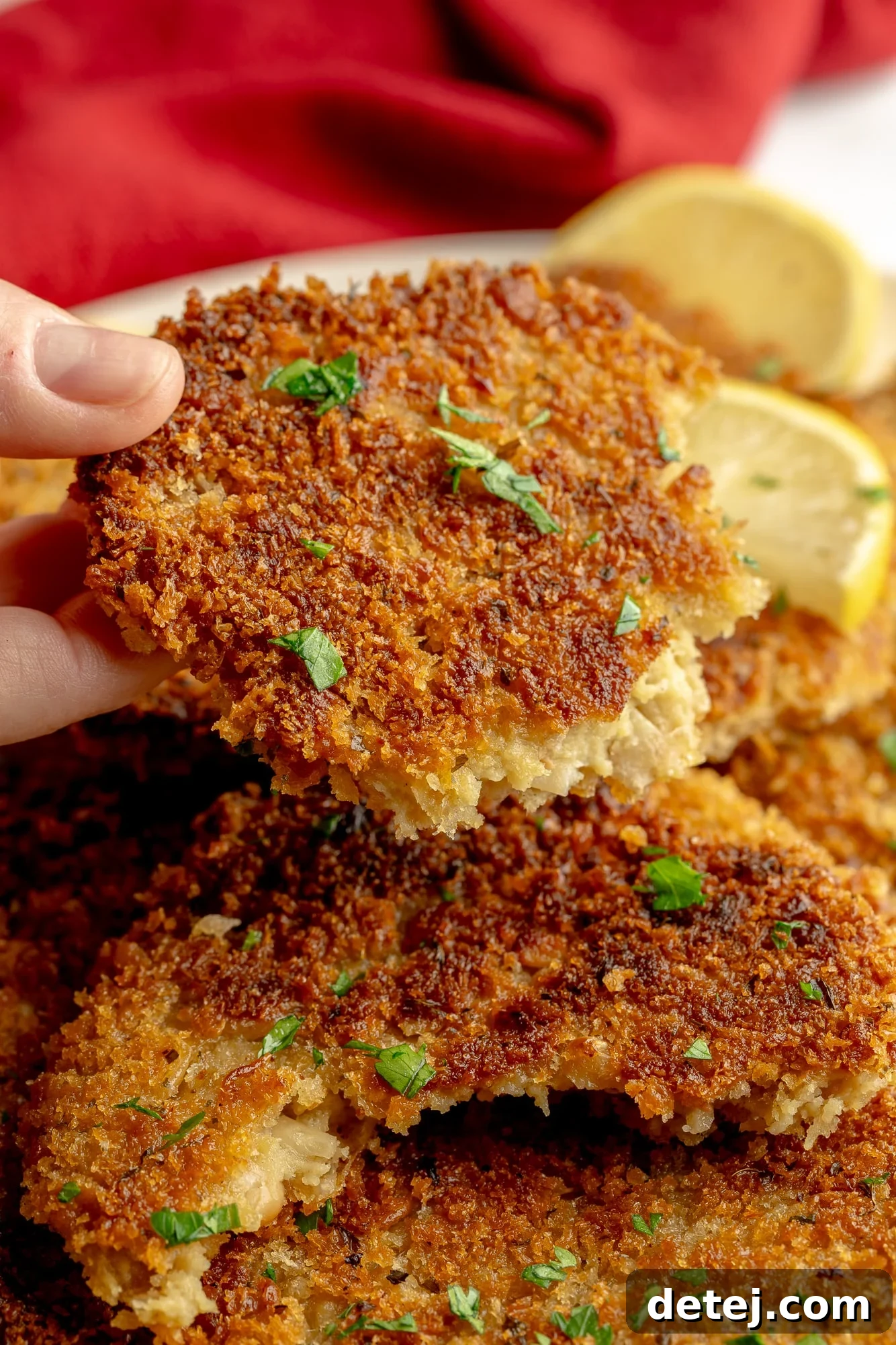 A woman's hand holding a vegan cutlet cut in half, revealing the meaty interior.