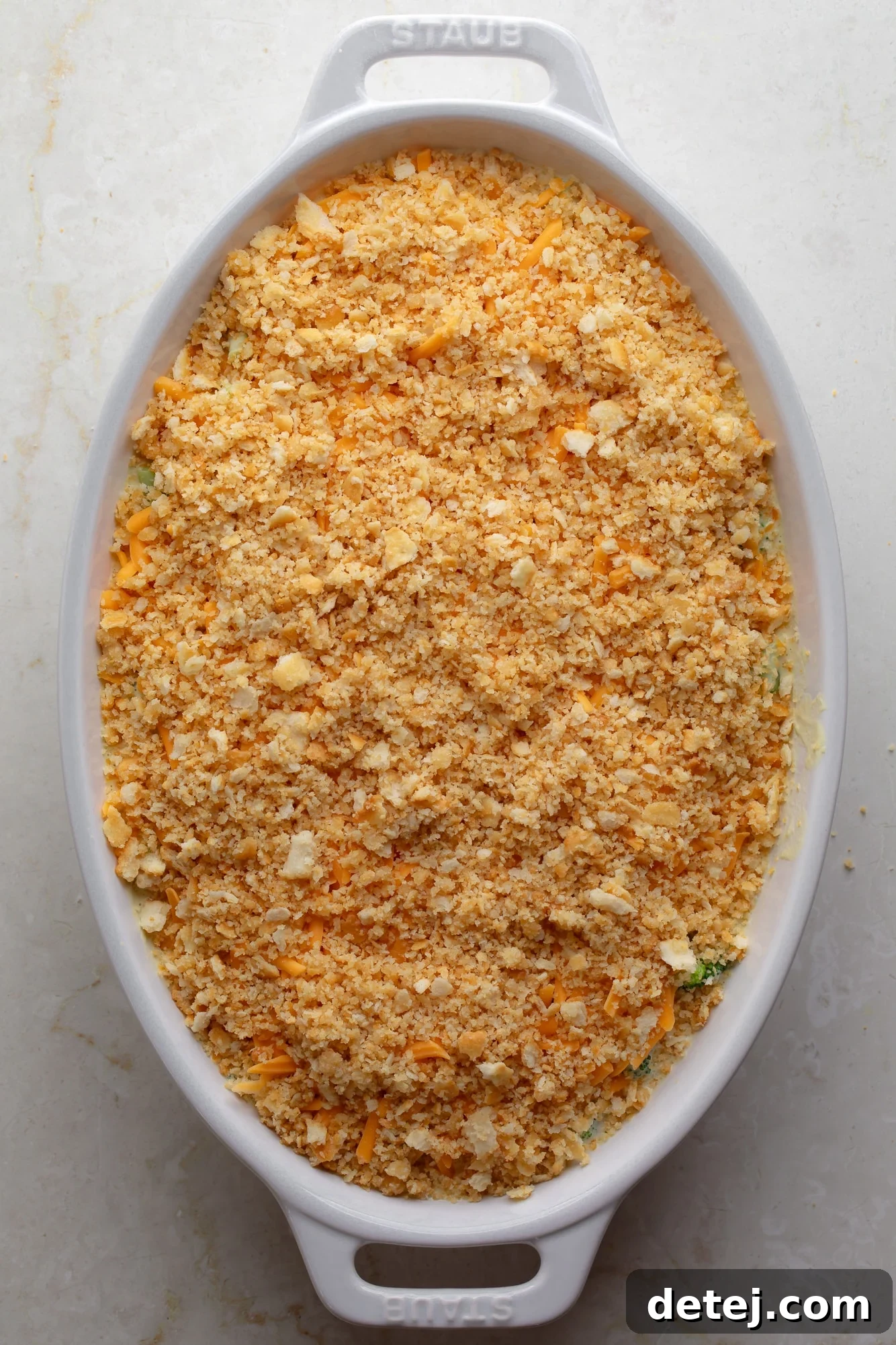 An inviting overhead view of a golden cracker crumb-topped vegan broccoli casserole, perfectly baked in a large casserole dish, ready to be served.