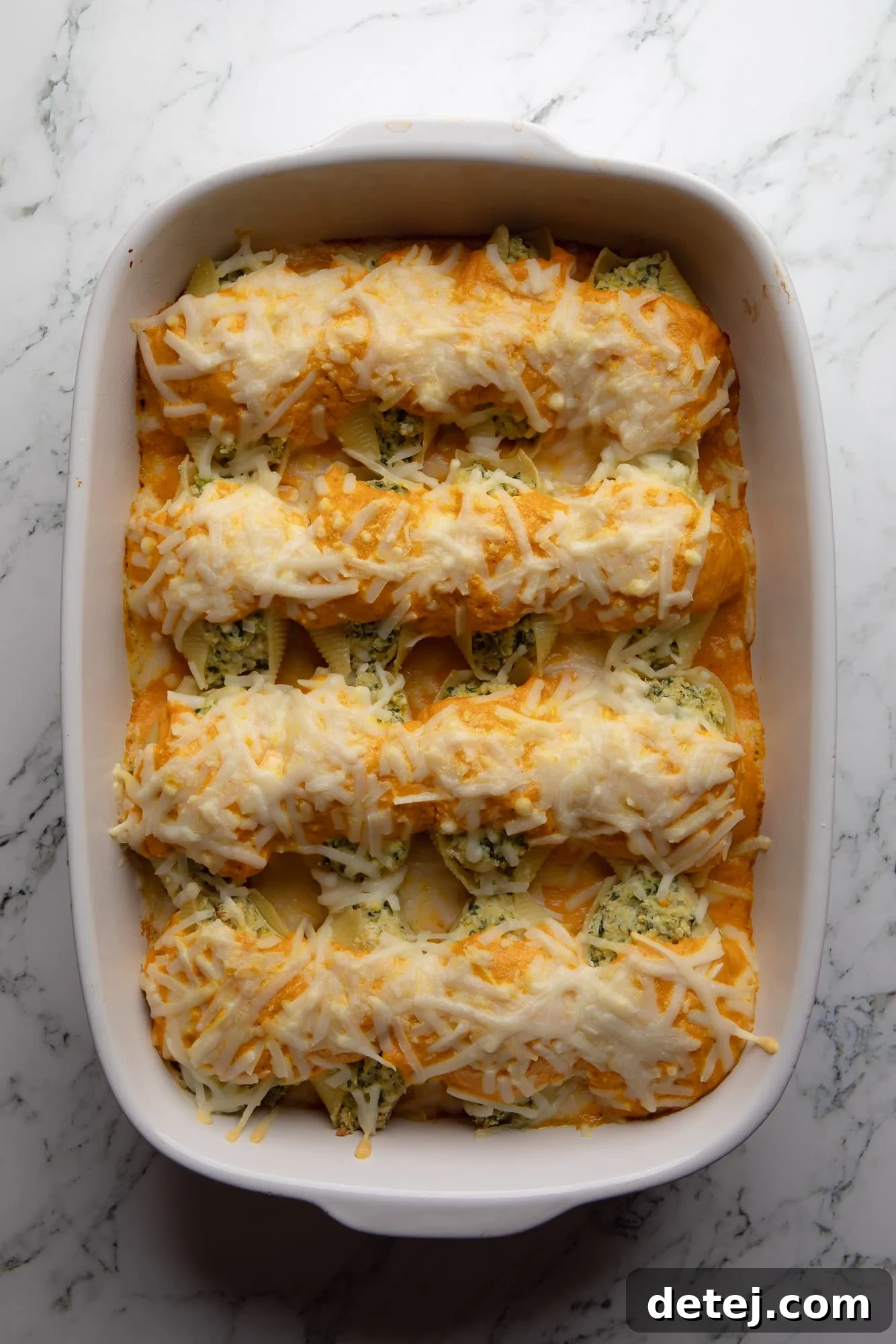 Overhead view of a baking dish filled with golden-brown, baked vegan pumpkin stuffed shells, ready to be served.