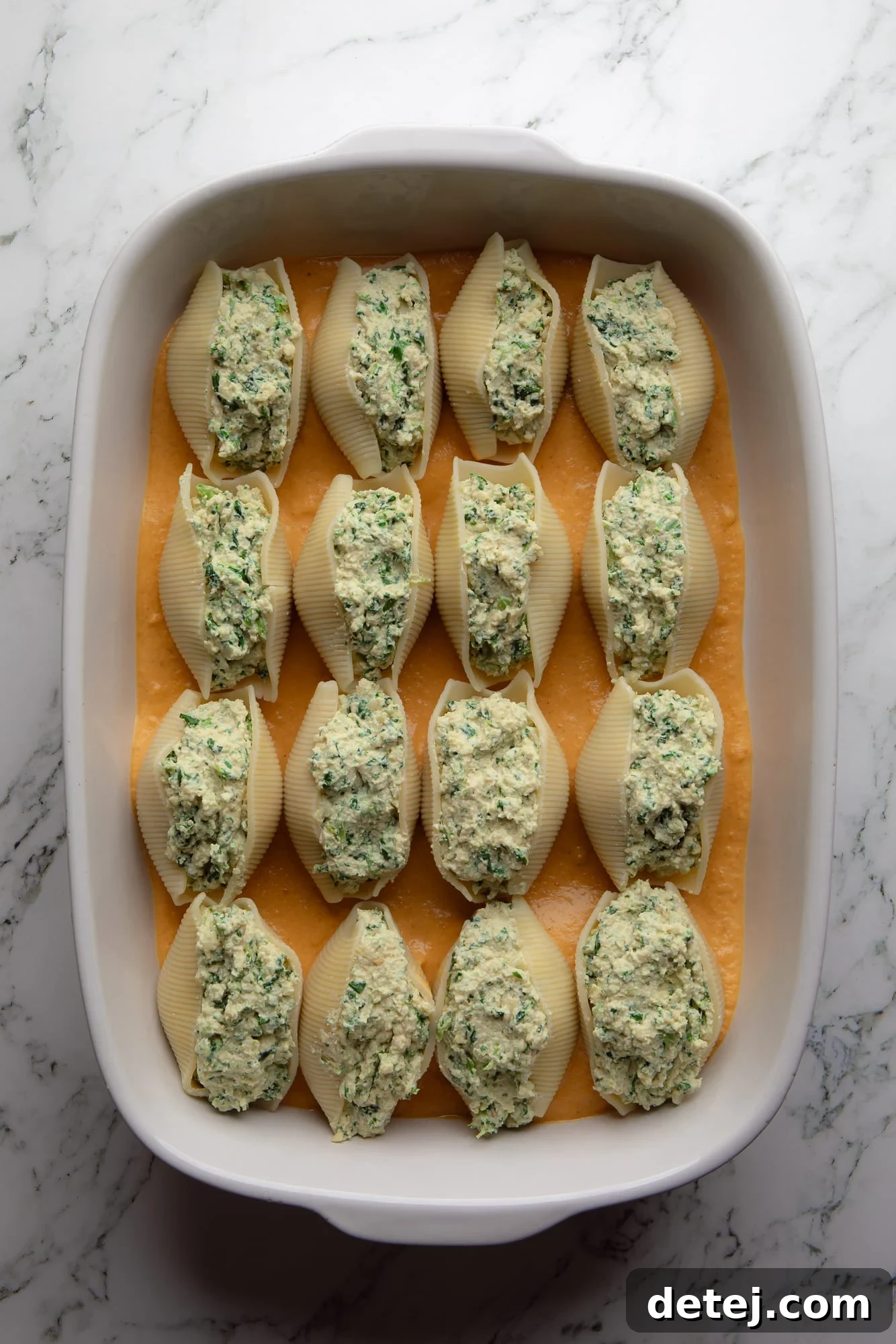 Overhead view of an assembled casserole dish, showing vegan pumpkin stuffed shells meticulously arranged before baking.