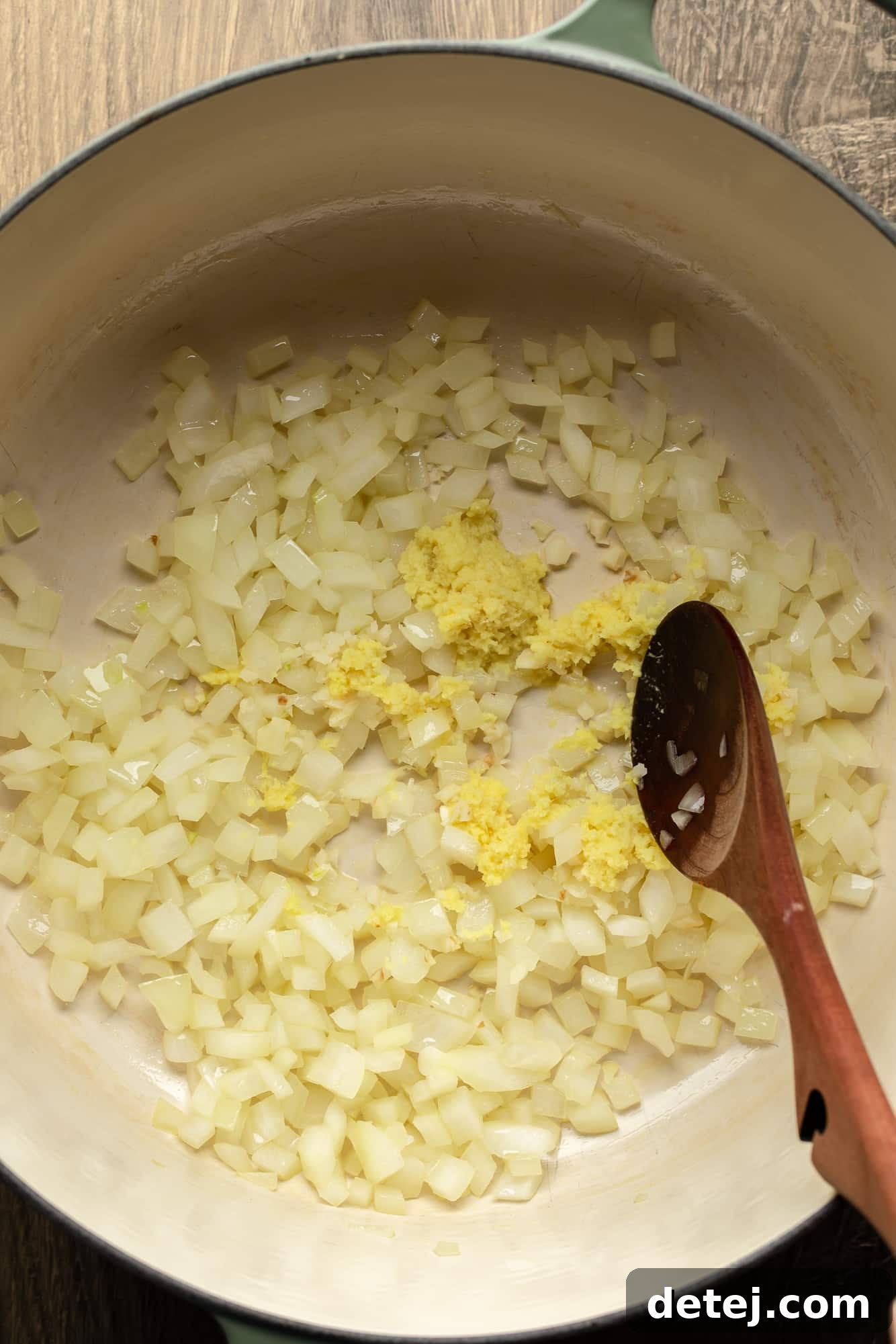 Golden Carrot Ginger Comfort 4 cooking chopped onions and ginger for carrot and ginger soup in a large pot.