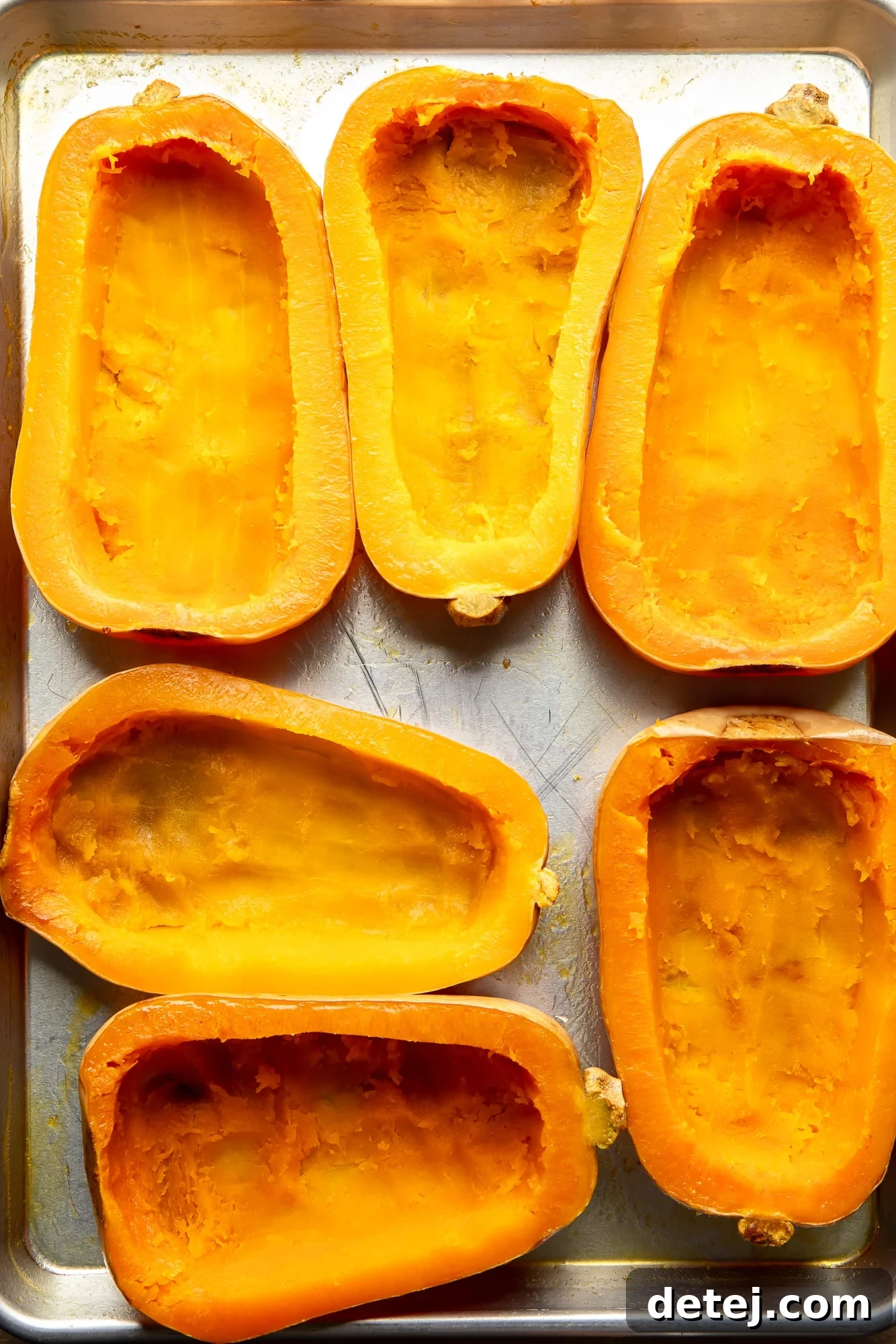 roasted and hollowed out butternut squashes on a baking sheet, ready for filling.