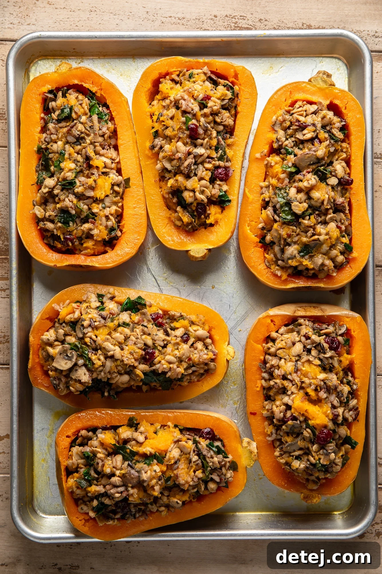 overhead view of stuffed butternut squashes baking on a sheet pan, showing their golden tops.