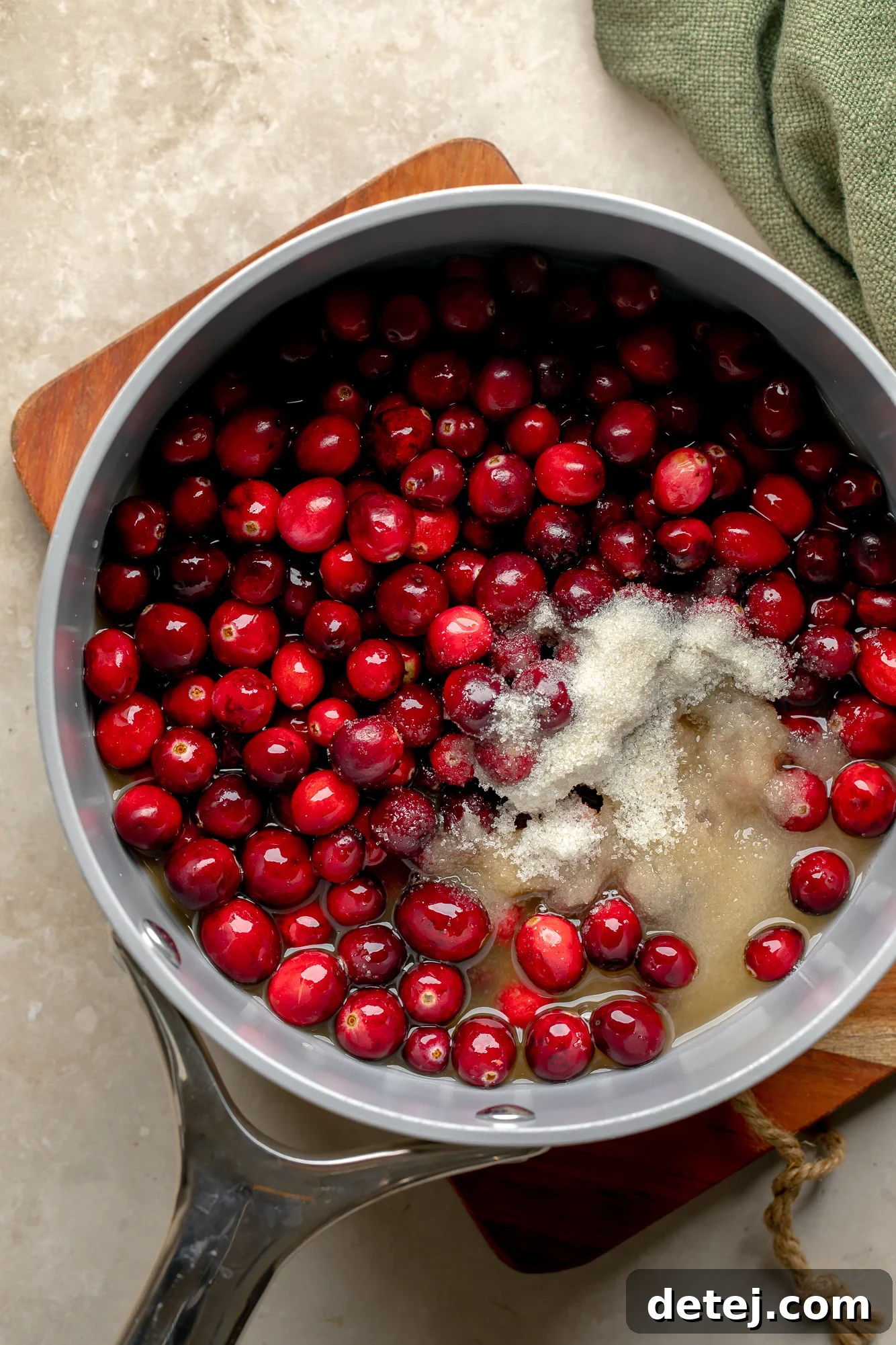 Ruby Orange Cranberry Delight 4 overhead view of fresh cranberries, sugar, and orange juice for orange cranberry sauce in a saucepan.