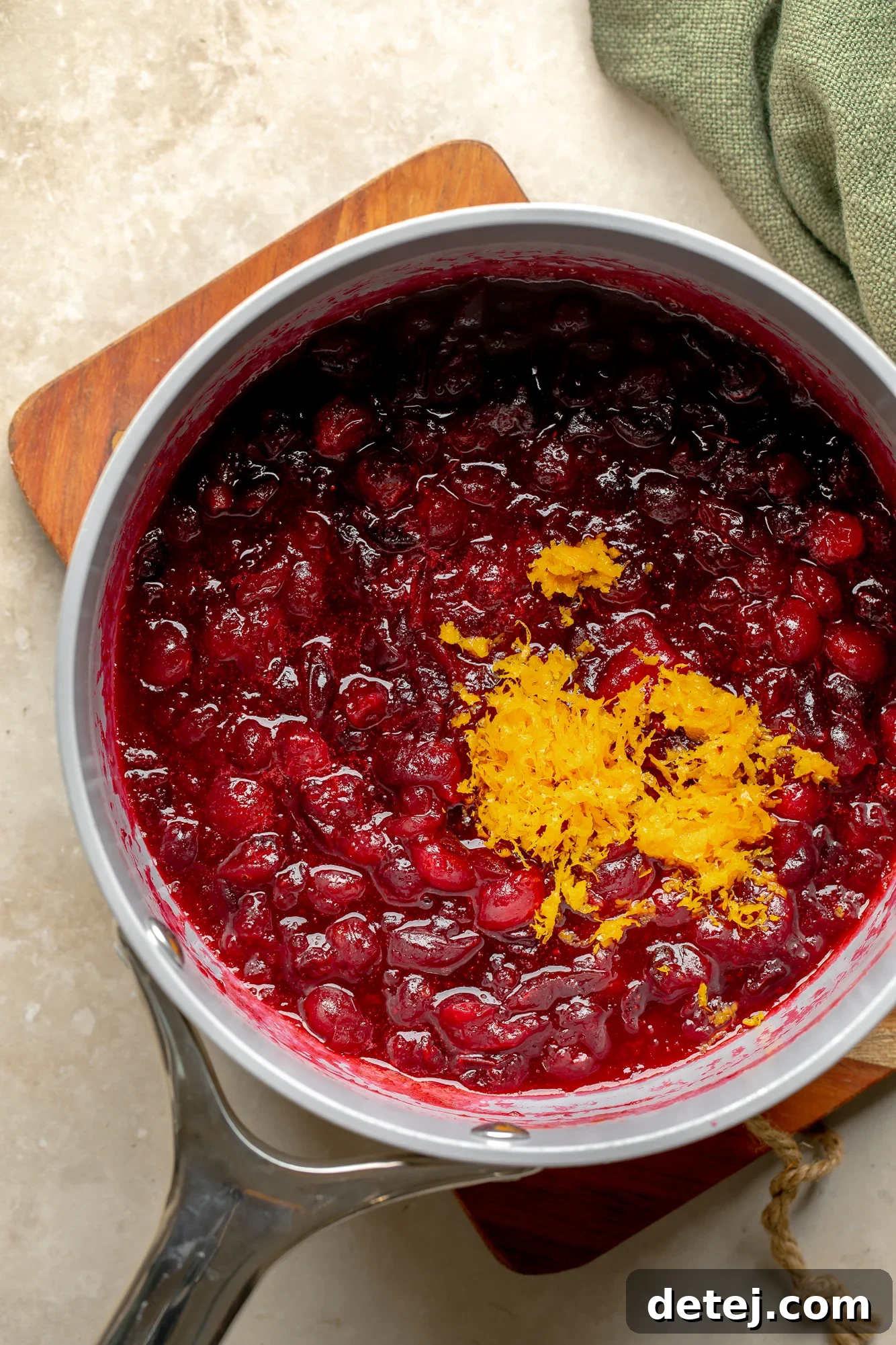 Ruby Orange Cranberry Delight 6 overhead view of orange cranberry sauce topped with orange zest in a saucepan.