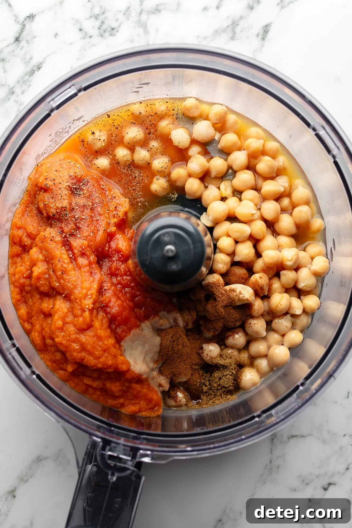overhead view of the ingredients for pumpkin hummus in a food processor.