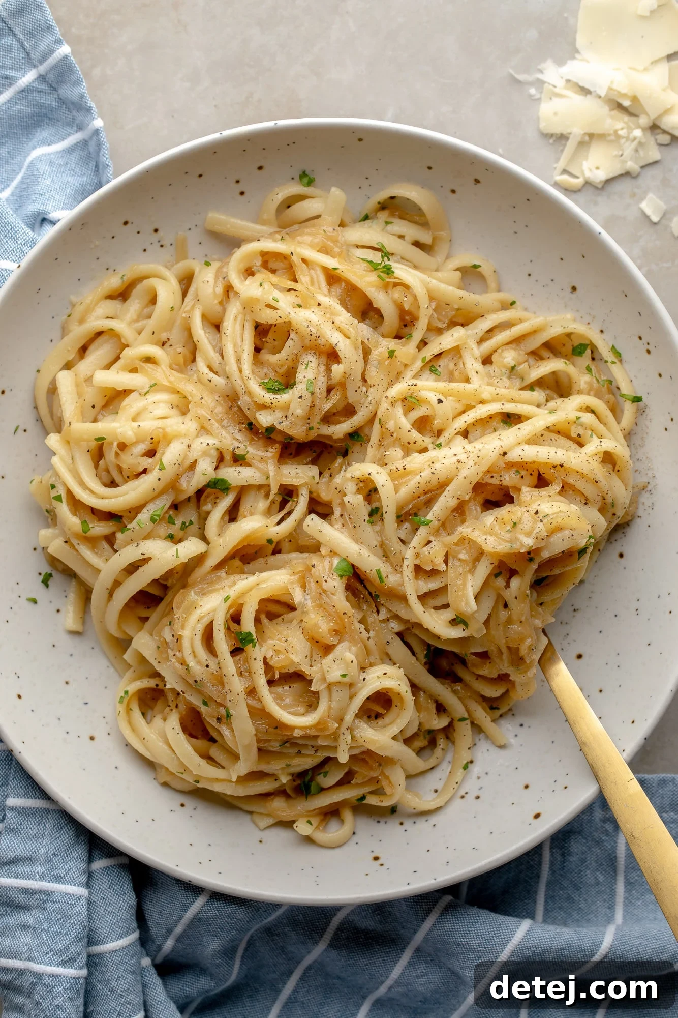 Overhead view of a beautiful bowl of vegan caramelized onion pasta, garnished with fresh parsley.