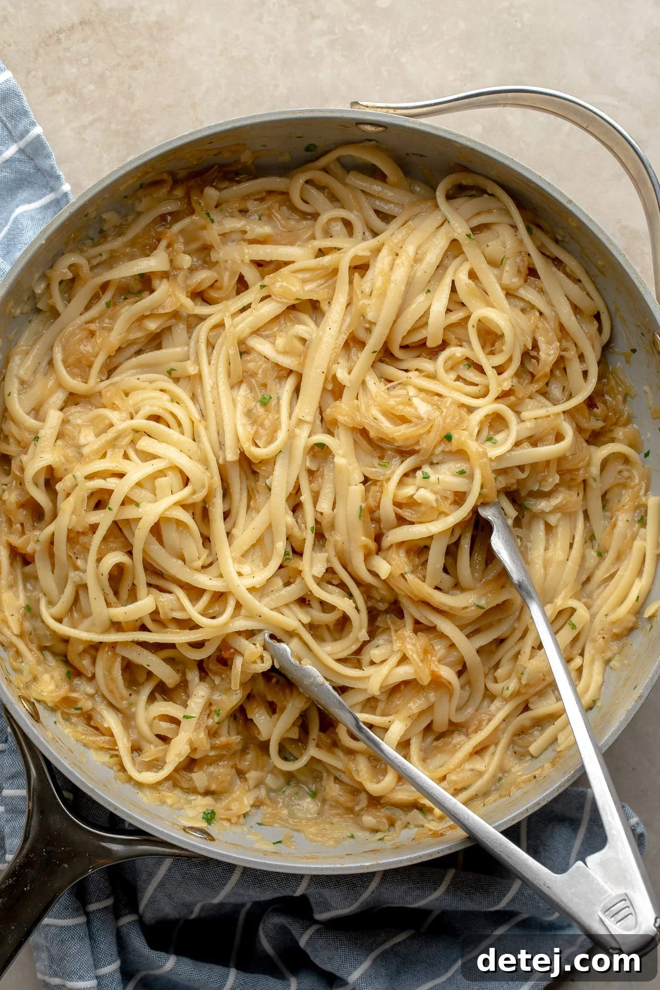 Overhead view of a skillet filled with a generous portion of vegan caramelized onion pasta, ready to be served.