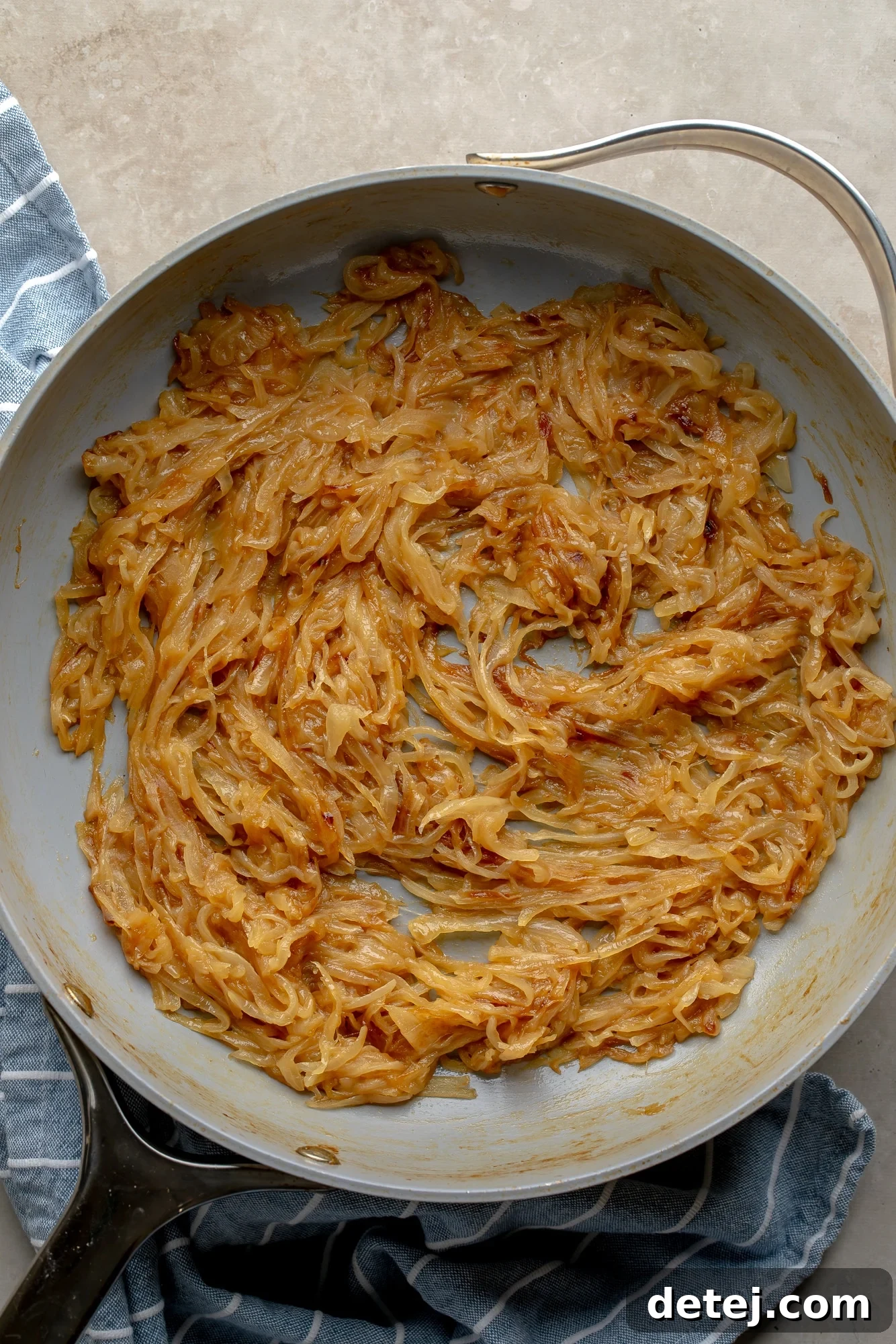 Close-up overhead view of beautifully caramelized onions, rich golden-brown and tender, in a large skillet.