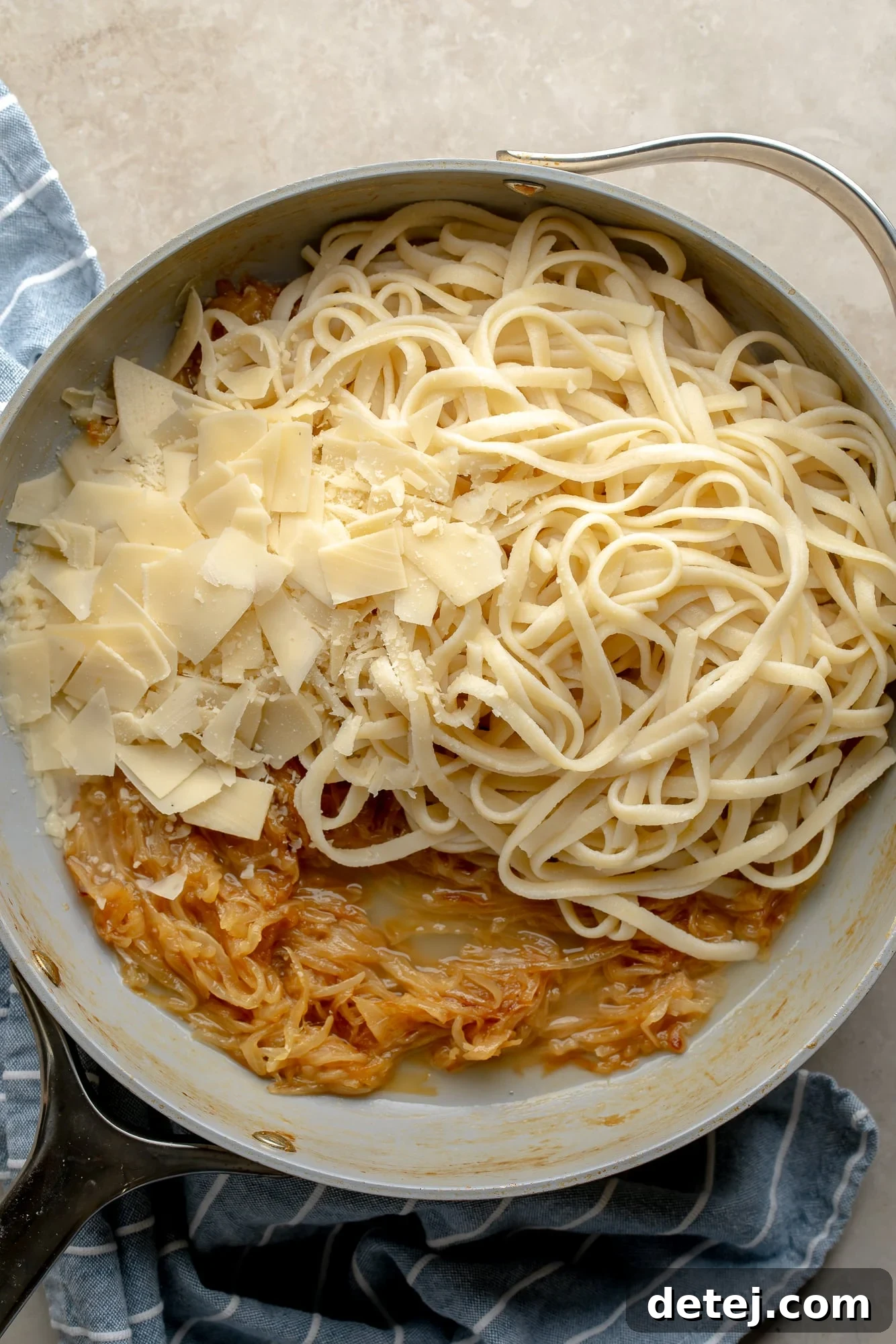 Overhead view of a skillet showcasing the final assembly of vegan caramelized onion pasta ingredients, before mixing.