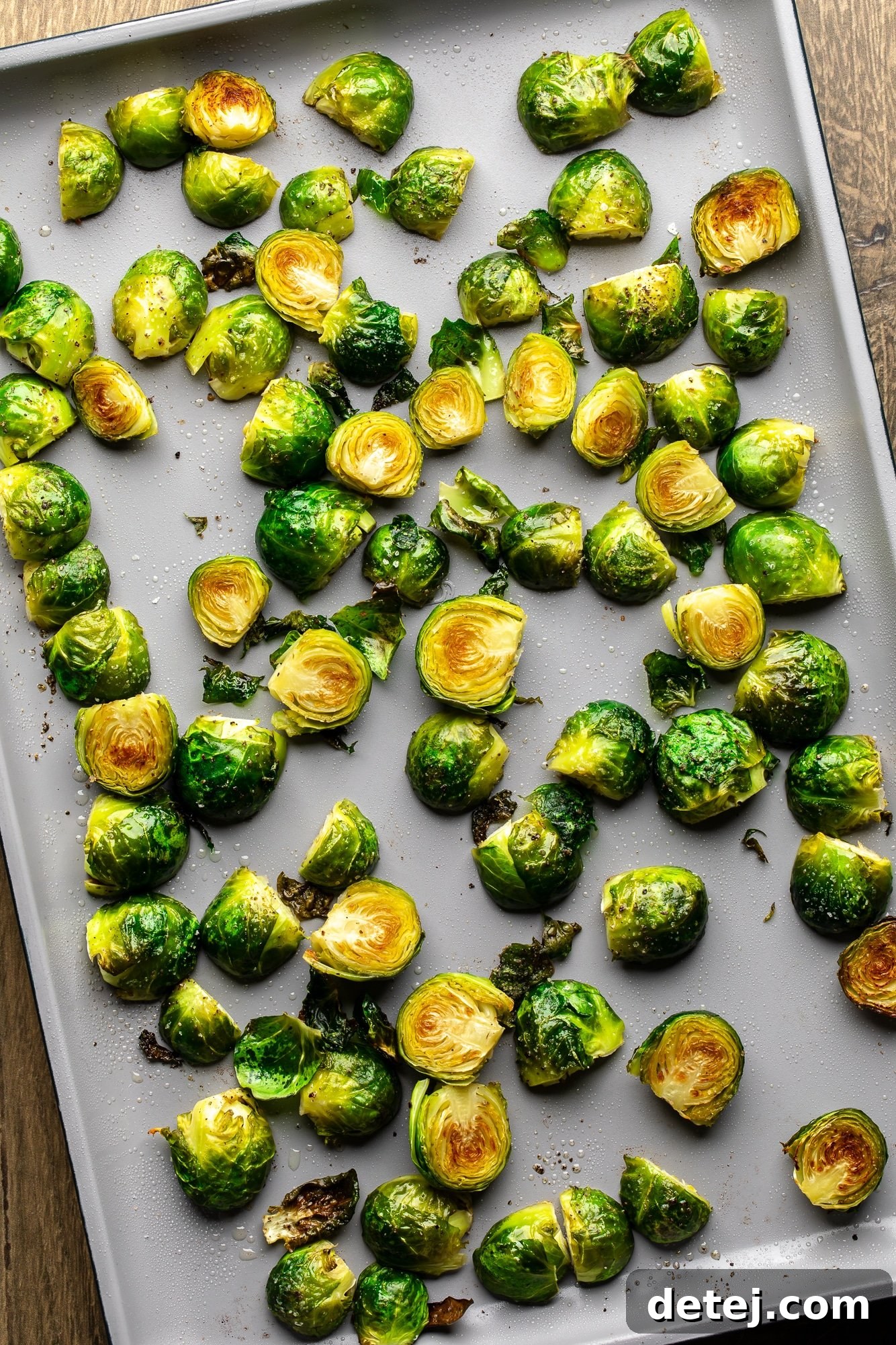 Brussels sprouts roasting on a baking sheet, perfectly golden brown and caramelized on the cut side, indicating optimal cooking for the salad.