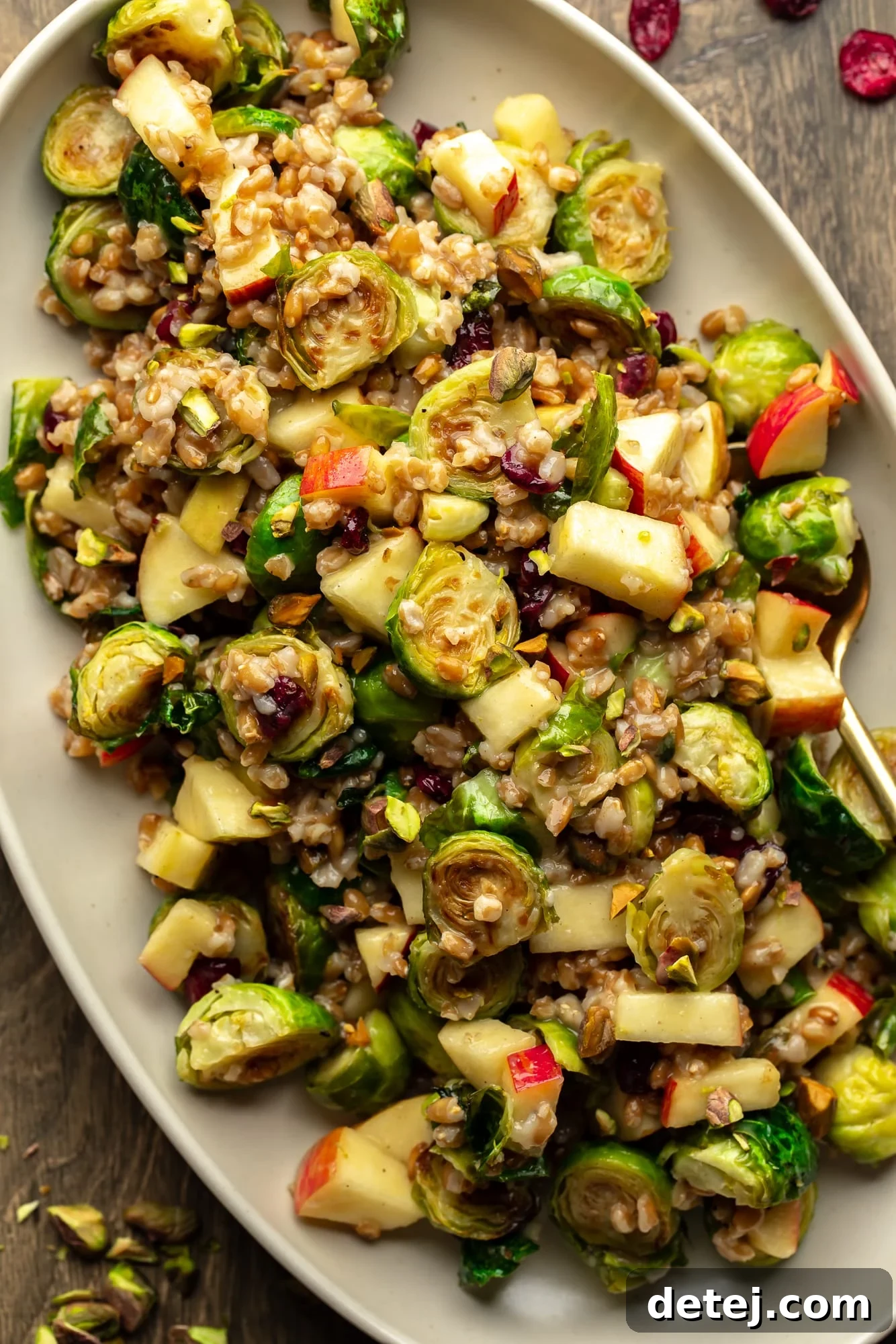 A beautifully presented warm brussels sprouts salad on a large white serving dish, garnished and ready to be enjoyed, perfect for a festive table.