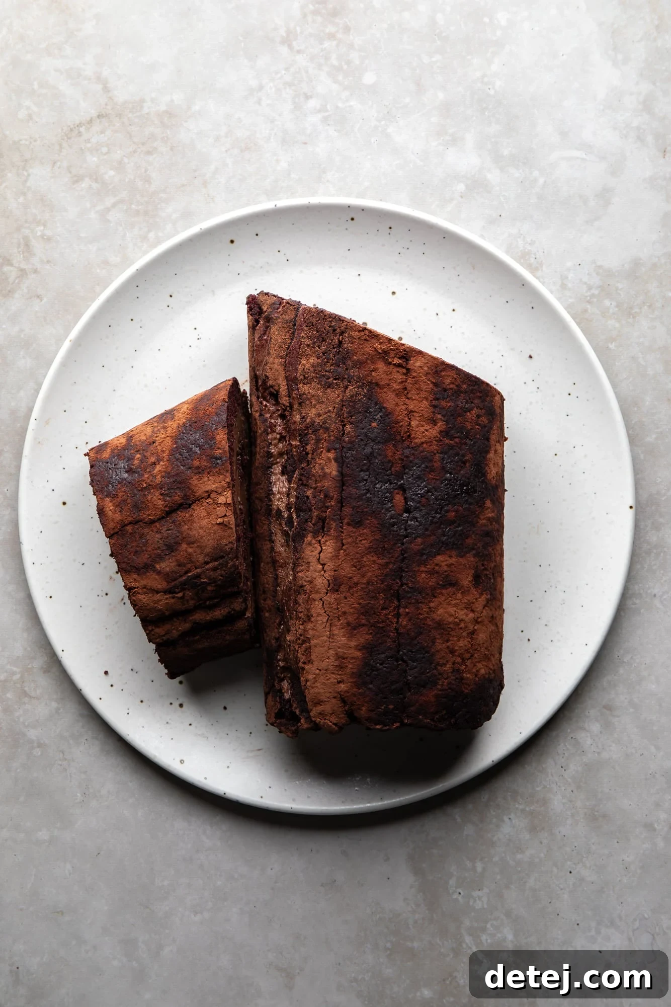 overhead view of an undecorated yule log cake on a white plate.