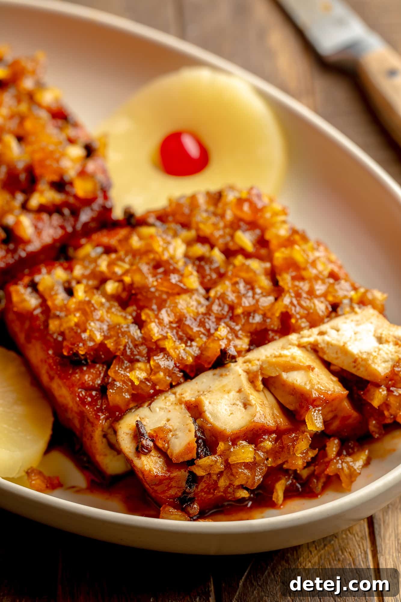 side view of a sliced pineapple glazed tofu roast in a serving dish.