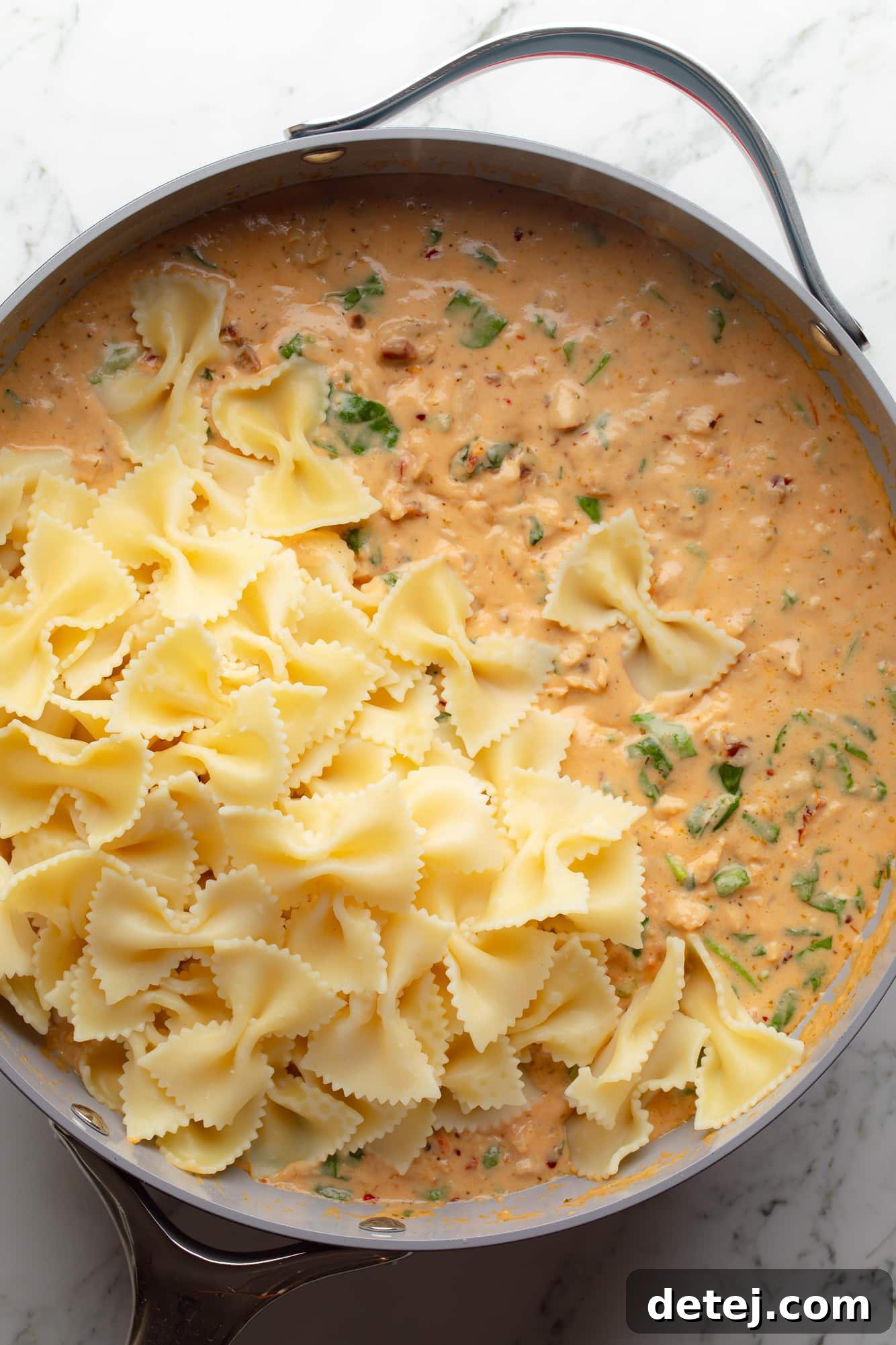 overhead view of cooked pasta in a vegan marry me pasta sauce in a large skillet.
