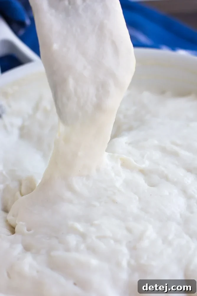 a spatula pulling up on vegan mozzarella to show how stretchy it is.