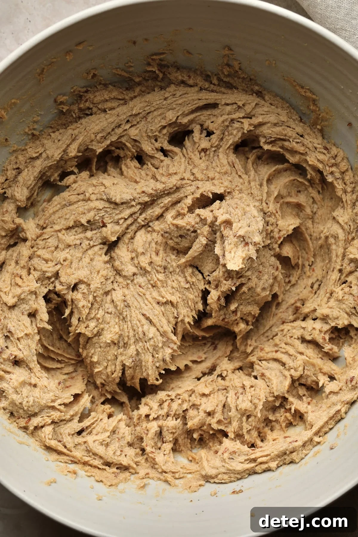 The wet batter, a smooth, light beige mixture, perfectly creamed in a large mixing bowl, ready for the dry ingredients.