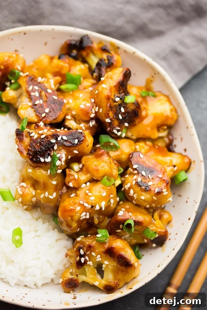 Delicious Sticky Sesame Cauliflower served with white rice in a bowl, garnished with sesame seeds