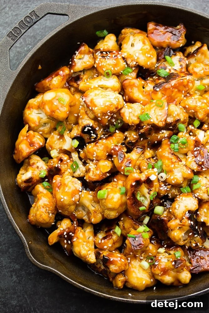 Crispy baked cauliflower florets coated in a rich, sticky sesame sauce in a cast iron pan