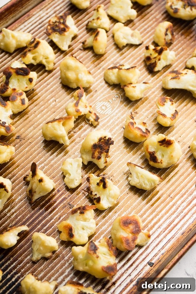 Golden brown and crispy roasted cauliflower florets filling a baking sheet, fresh out of the oven