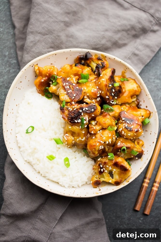 Appetizing bowl of white rice topped with generous portions of crispy sticky sesame cauliflower