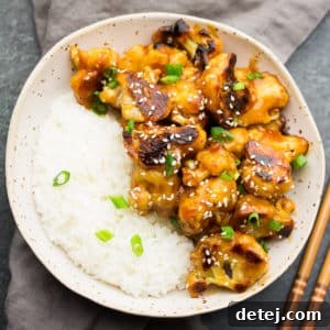 Overhead shot of a bowl of Sticky Sesame Cauliflower with rice, garnished with green onions
