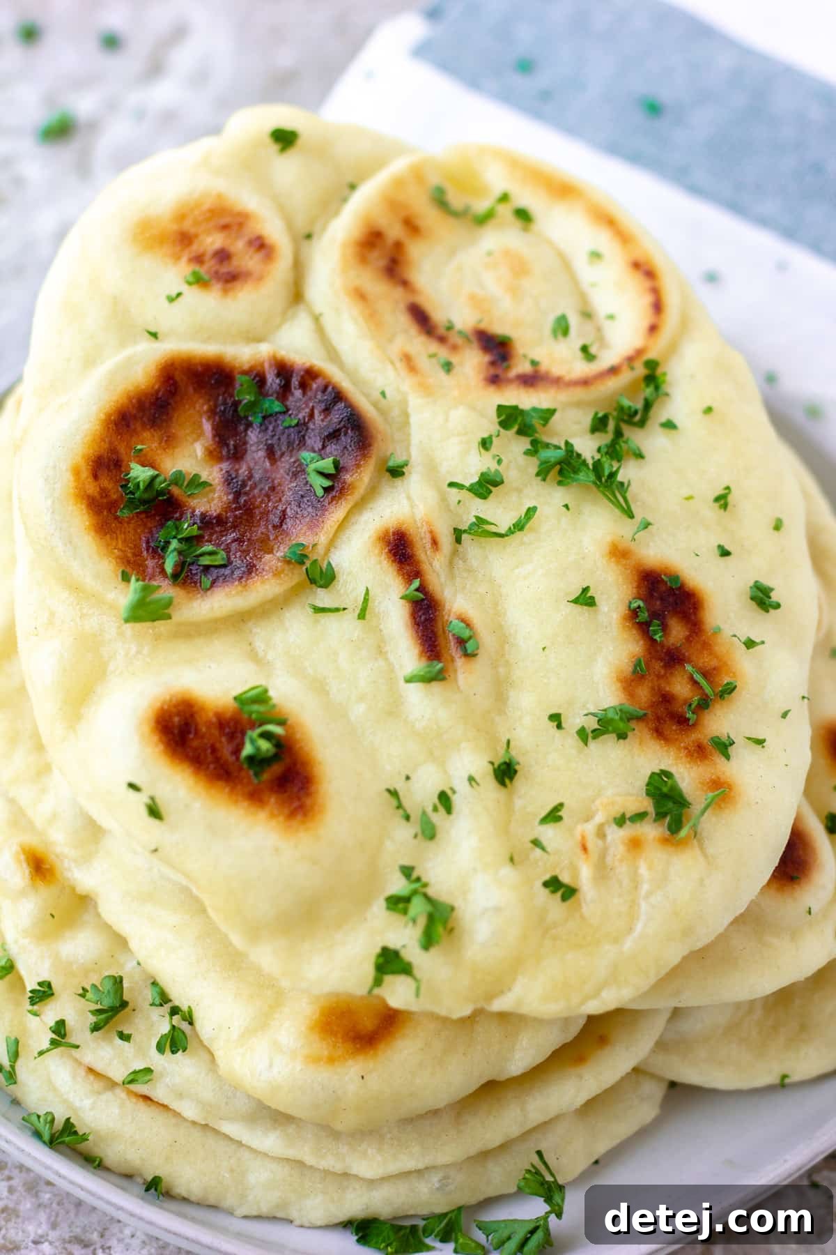 Freshly baked vegan naan stacked on a grey background, ready to be served with Indian dishes.