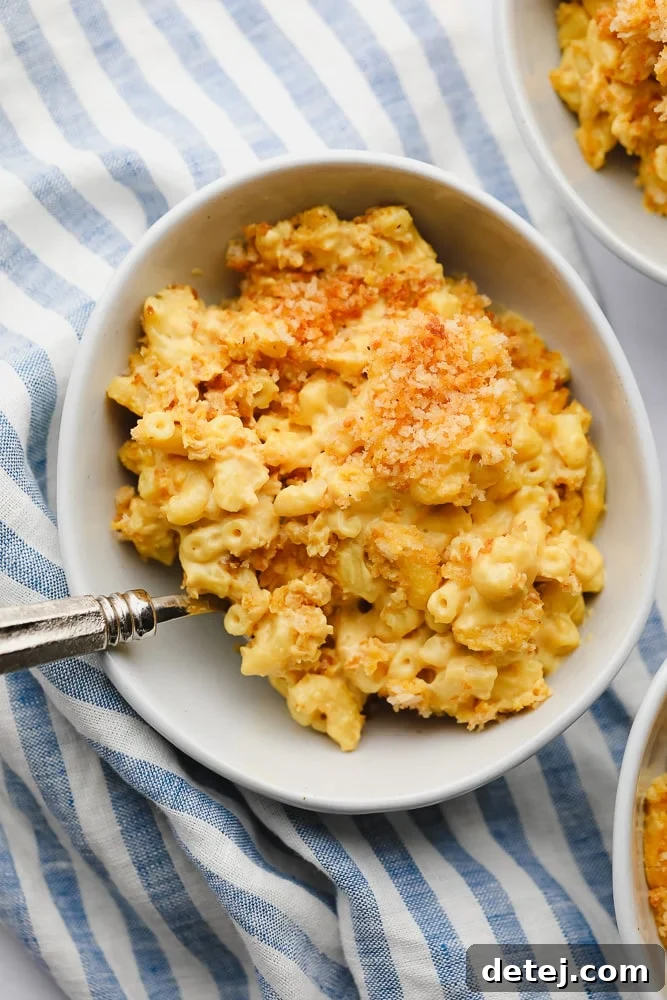 A large bowl of creamy vegan mac and cheese next to a blue and white striped towel, highlighting its appealing texture.