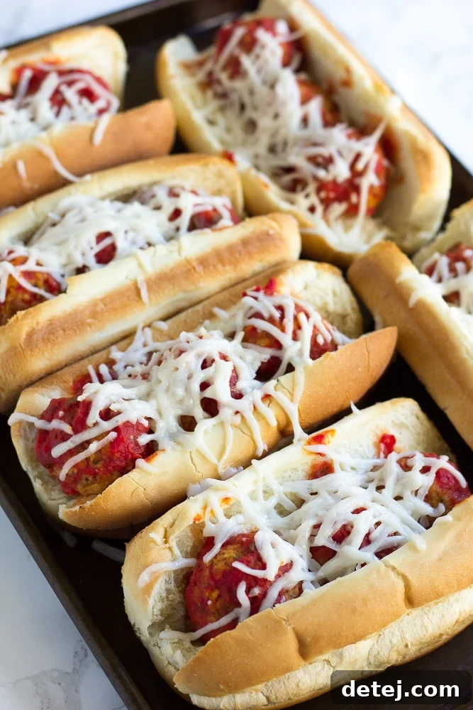 Close-up view of a baked vegan meatball sub, showing melted cheese and savory meatballs.