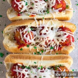 Three oven-baked vegan meatball subs on a wooden board