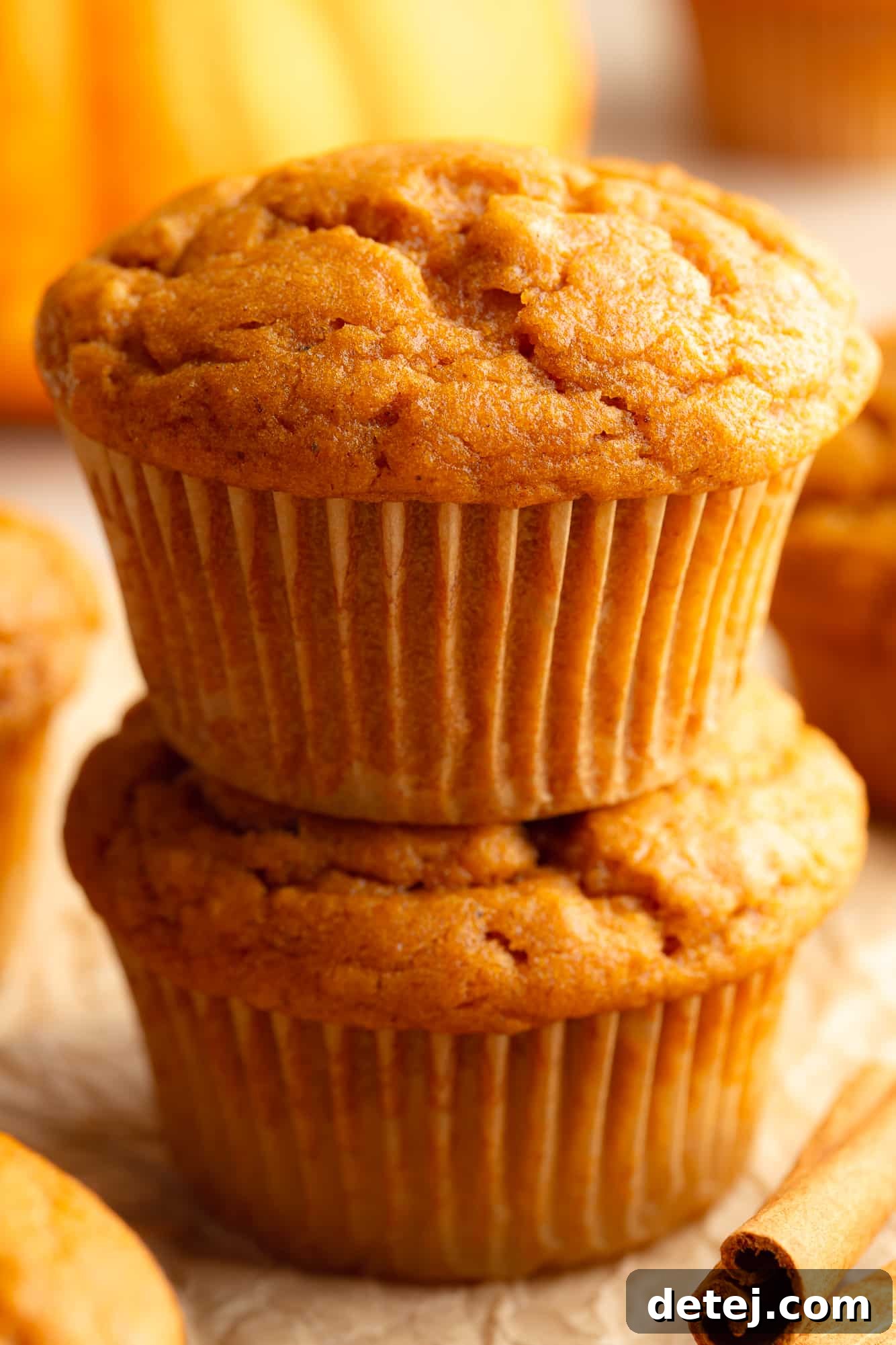 Two Vegan Pumpkin Muffins stacked on top of each other, showcasing their fluffy texture.