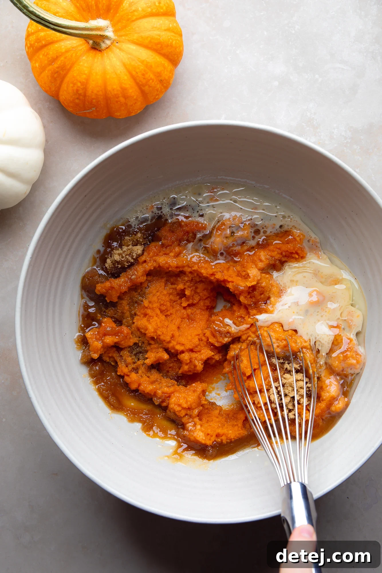 Whisking the wet ingredients for Vegan Pumpkin Muffins in a large bowl to ensure smoothness.