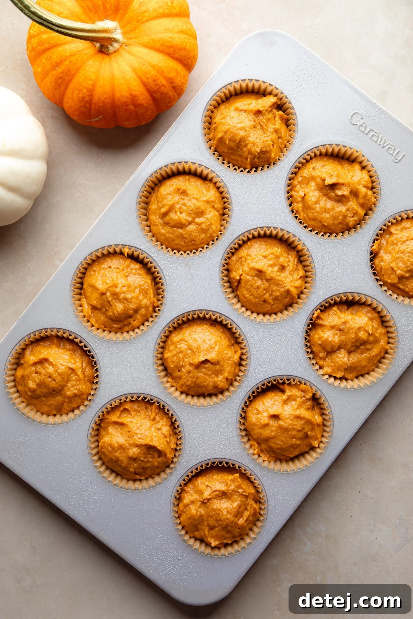 Overhead view of unbaked Vegan Pumpkin Muffins neatly portioned in a muffin tin, ready for the oven.