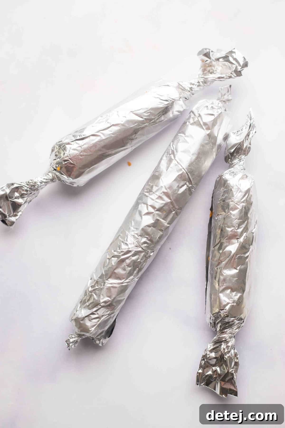 Plant-Powered Pepperoni 5 Three perfectly wrapped vegan pepperoni logs in aluminum foil, ready for baking.