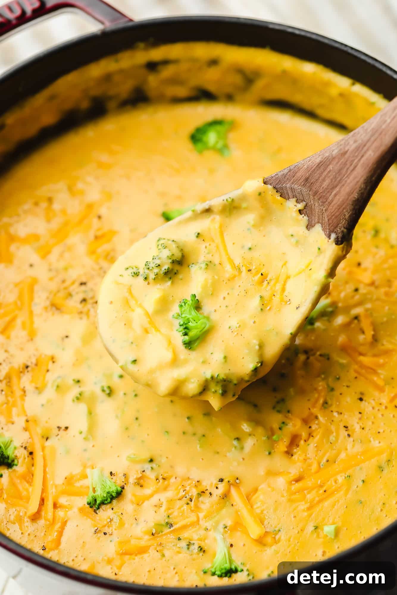 Velvety Vegan Broccoli Cheddar Soup 2 scooping up vegan broccoli cheddar soup with a wooden spoon.