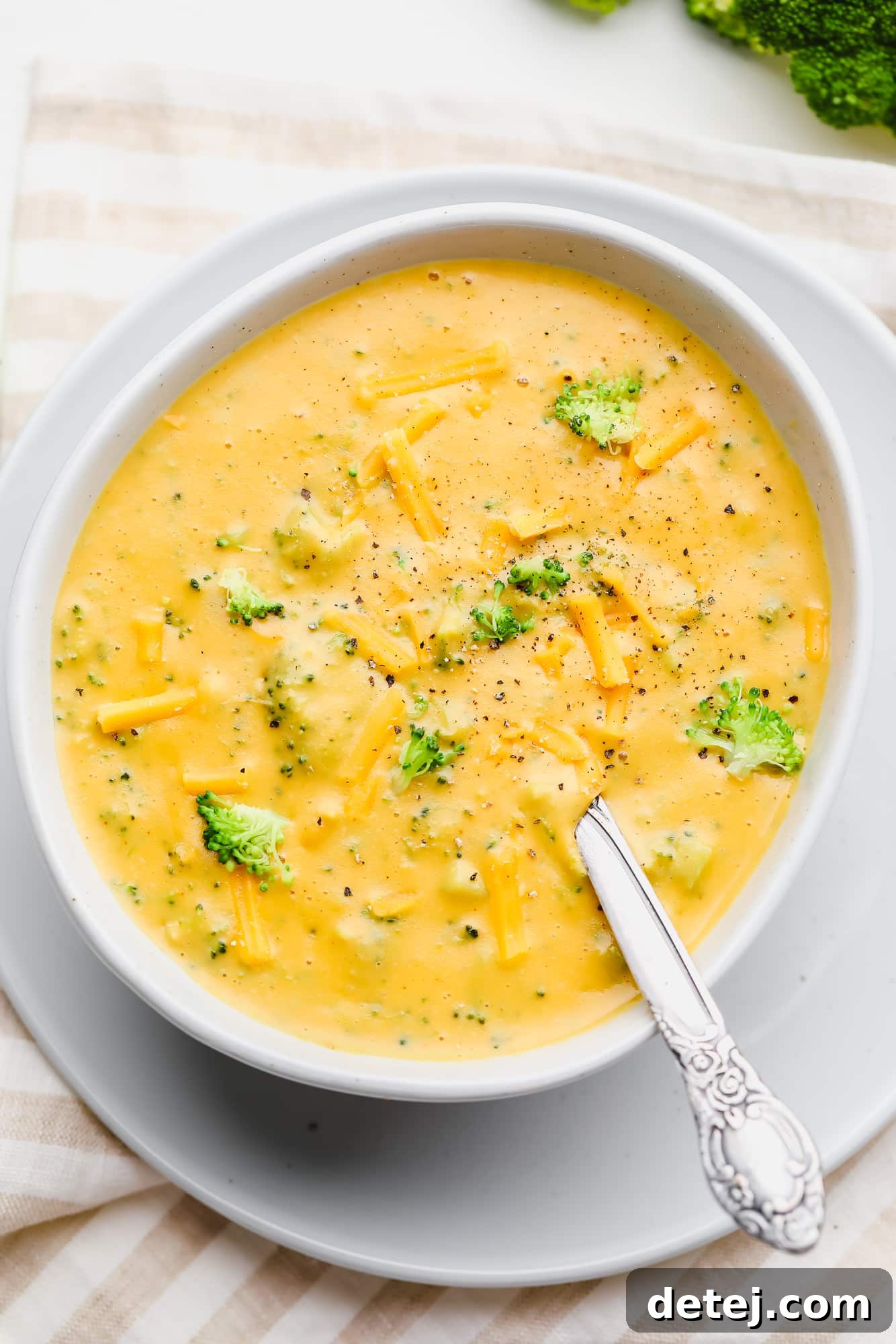 Velvety Vegan Broccoli Cheddar Soup 8 a white bowl filled with vegan broccoli cheddar soup and a spoon.