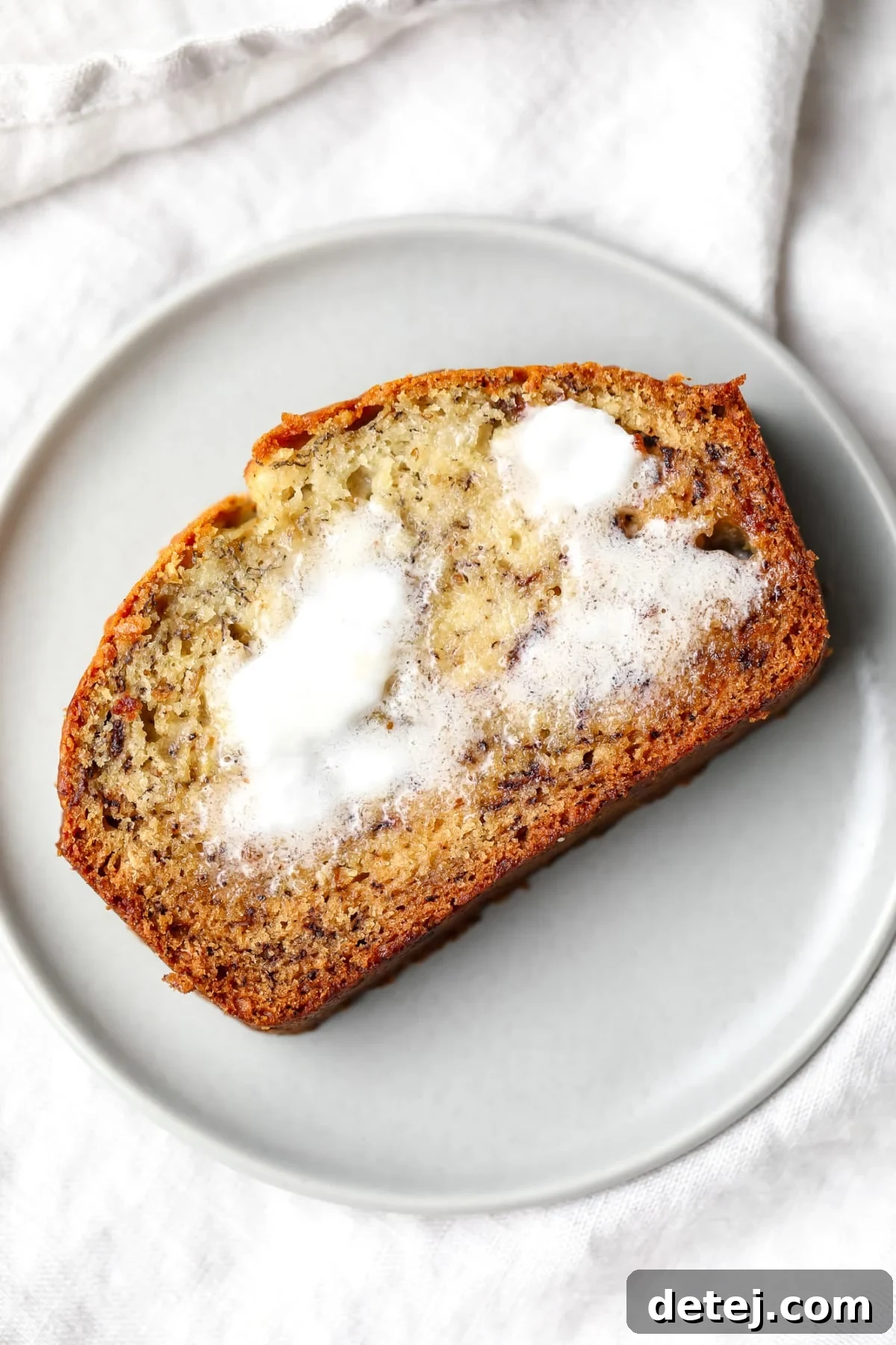 slice of bread with butter on grey towel