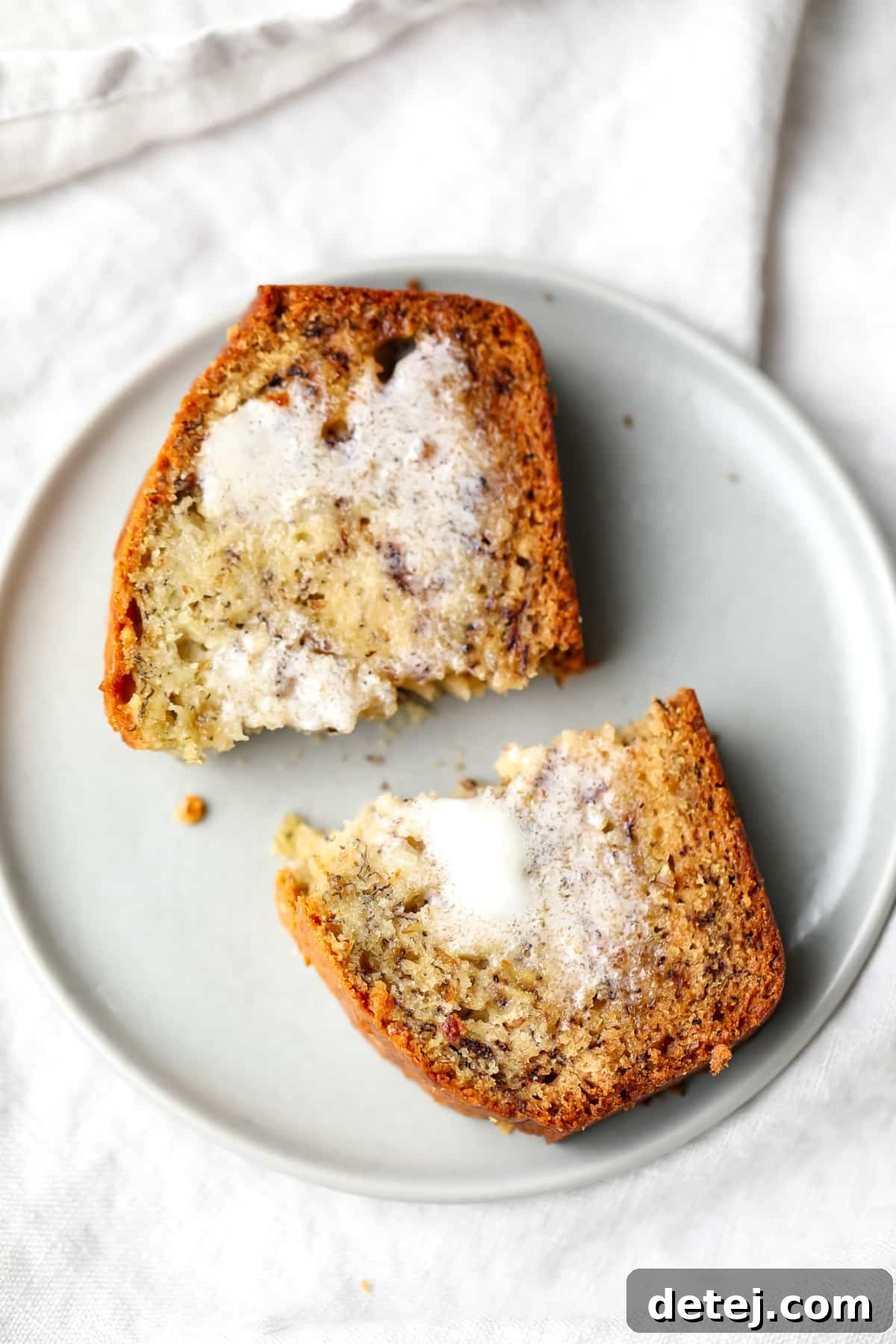 cut in half piece of banana bread with butter melted on it