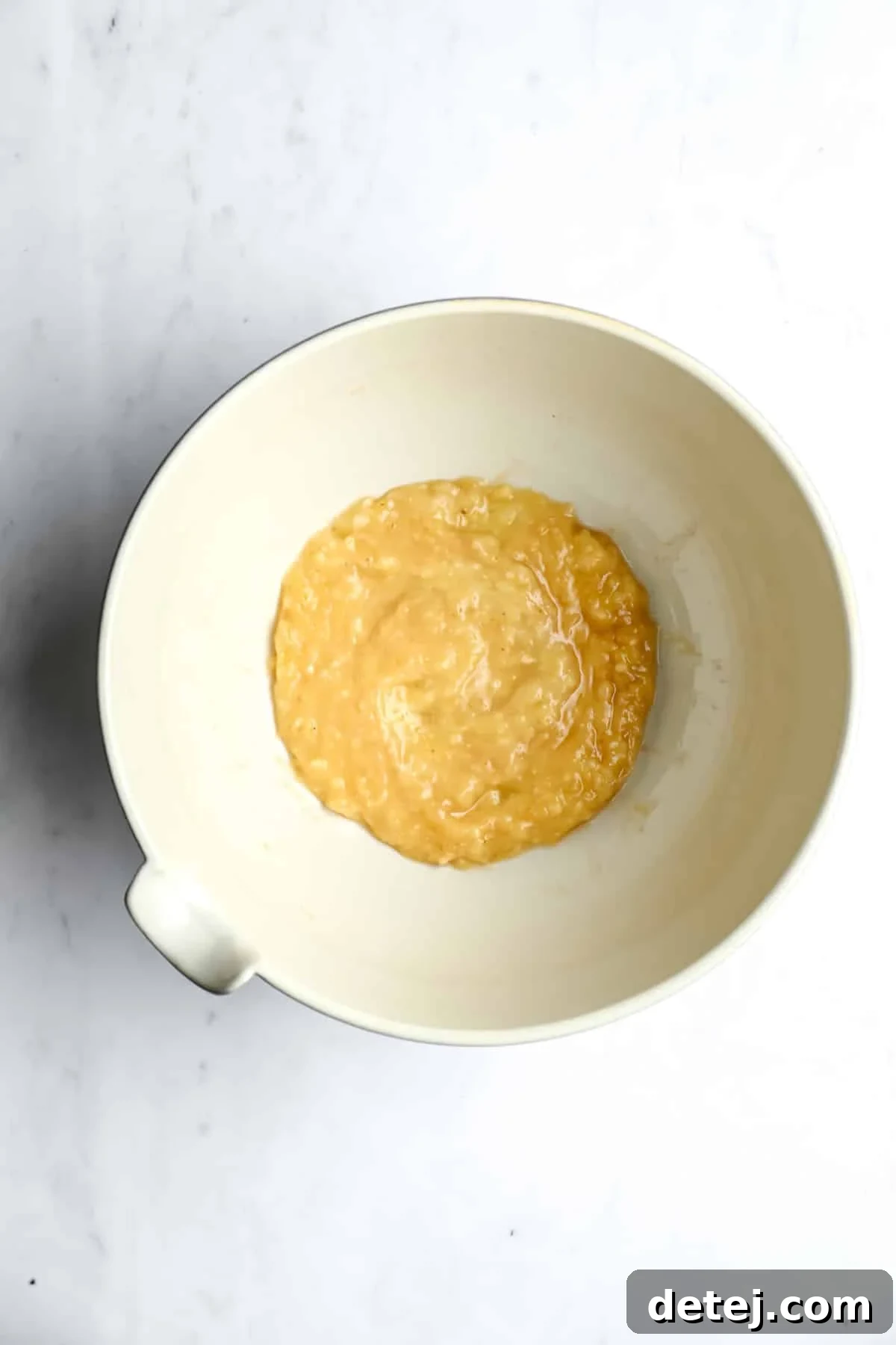 mashed bananas in a bowl on white backdrop